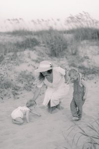 mom plays with daughters in the sand