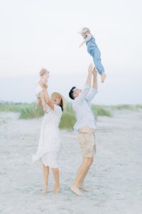 parents toss kids in the air on the beach
