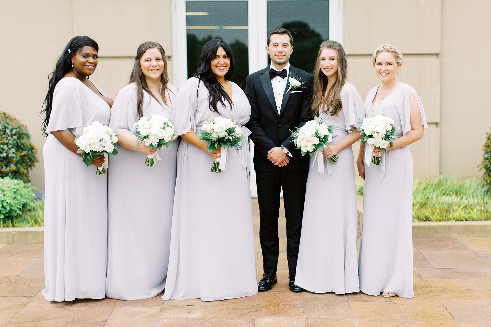 groom poses with bridesmaids