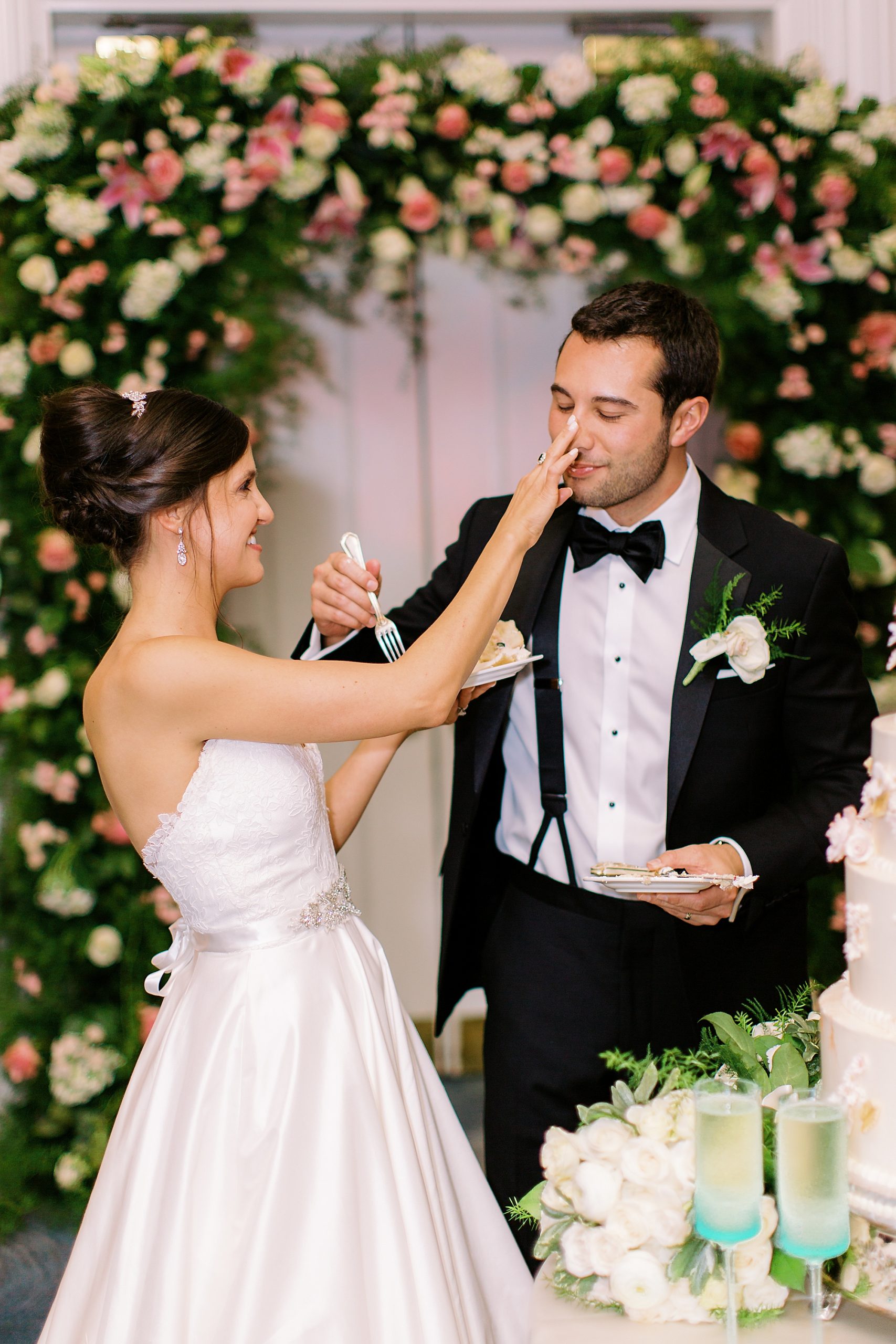 bride and groom smear icing on each other's noses during NC wedding reception