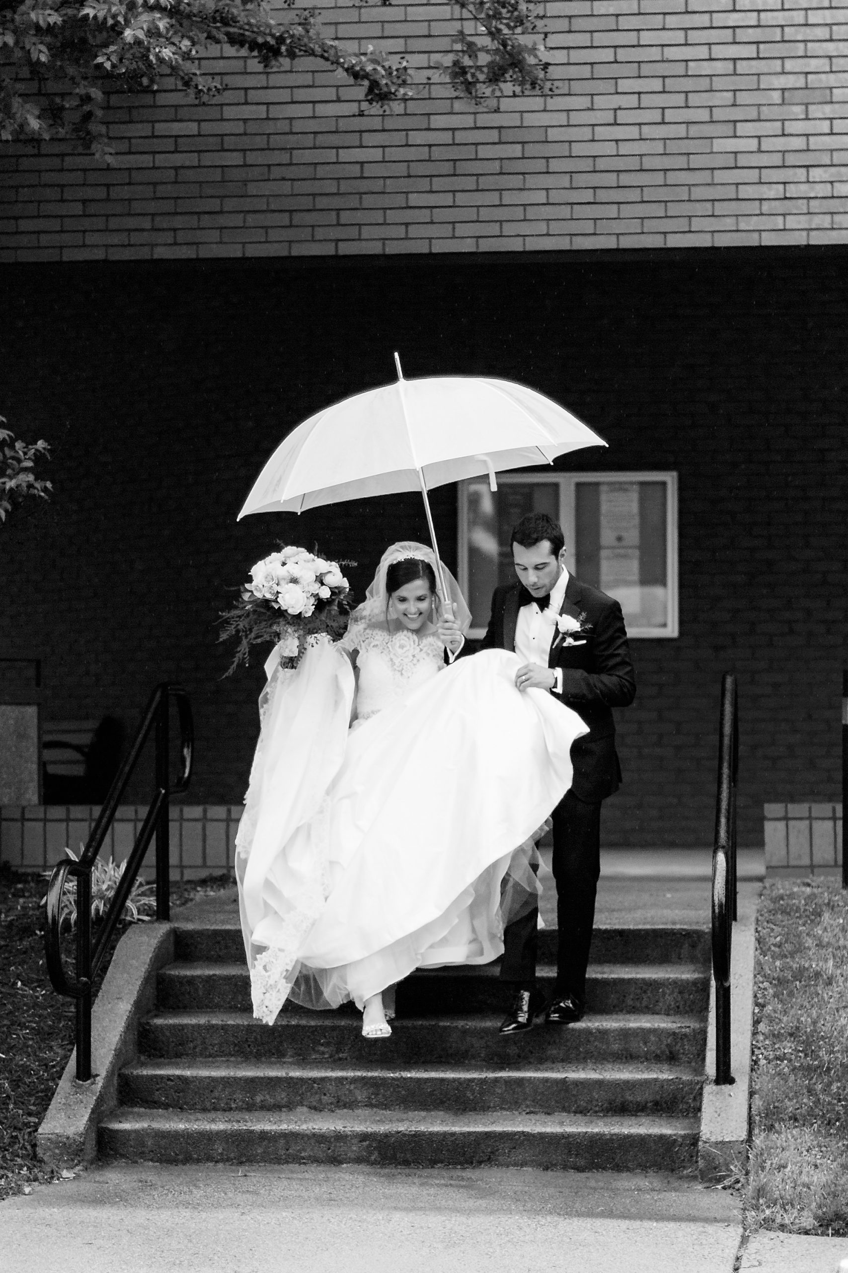groom helps bride leave church under umbrella
