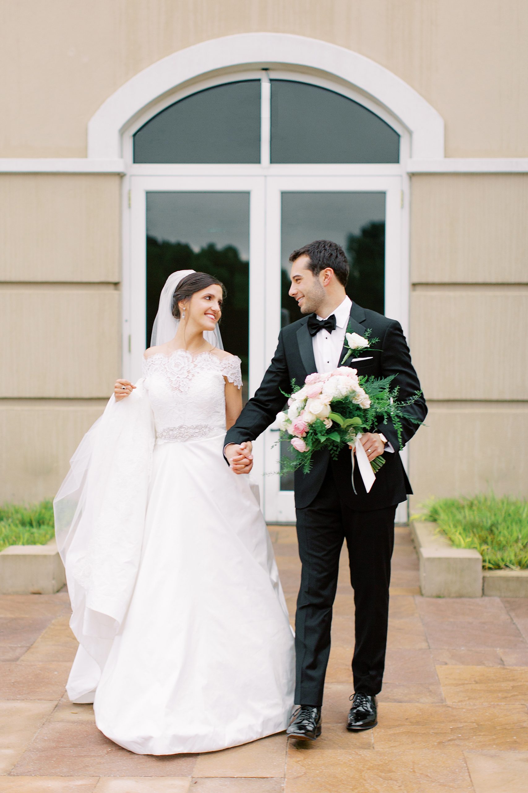 bride and groom hold hands walking outside Ballantyne Country Club