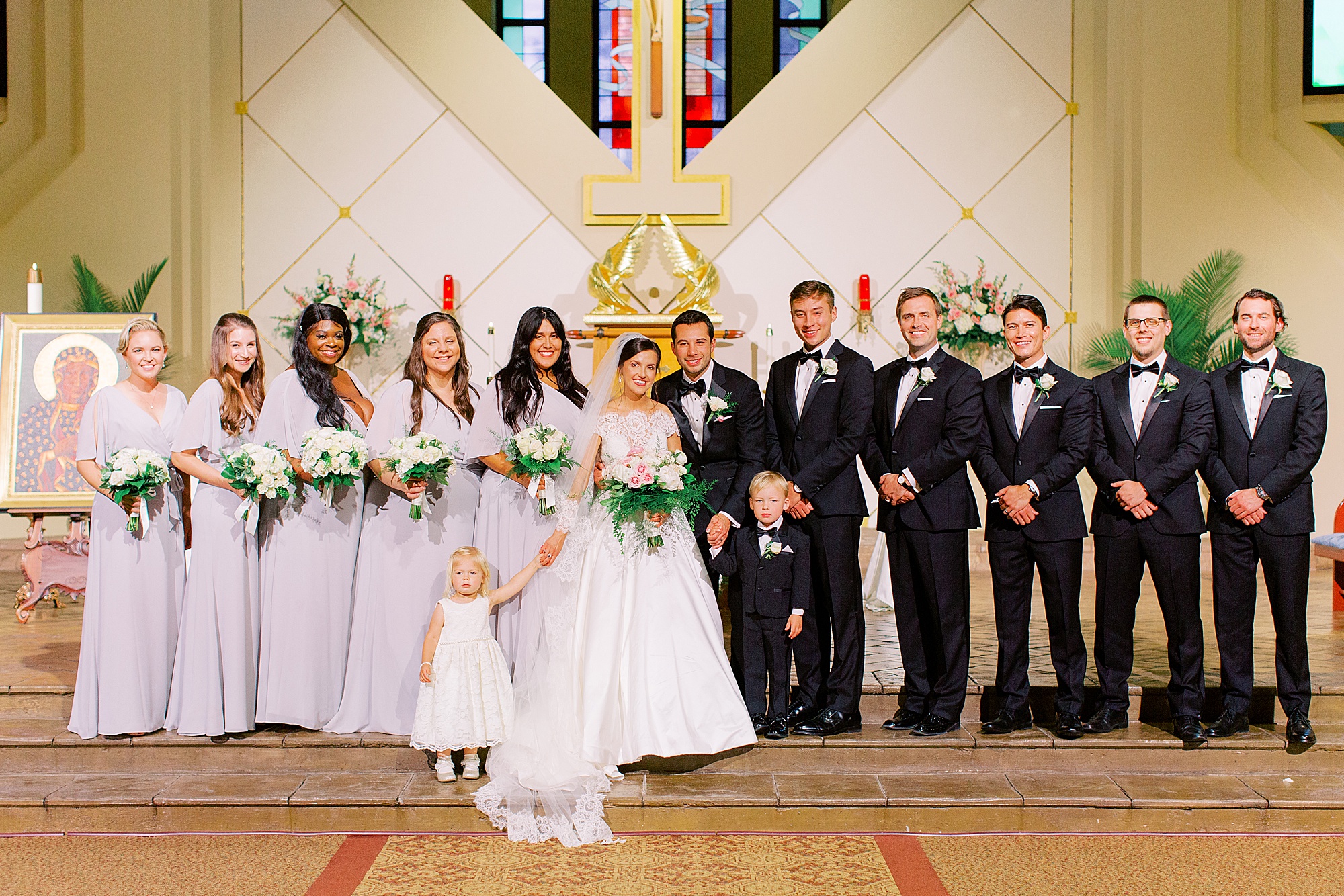 bride and groom pose with wedding party in church
