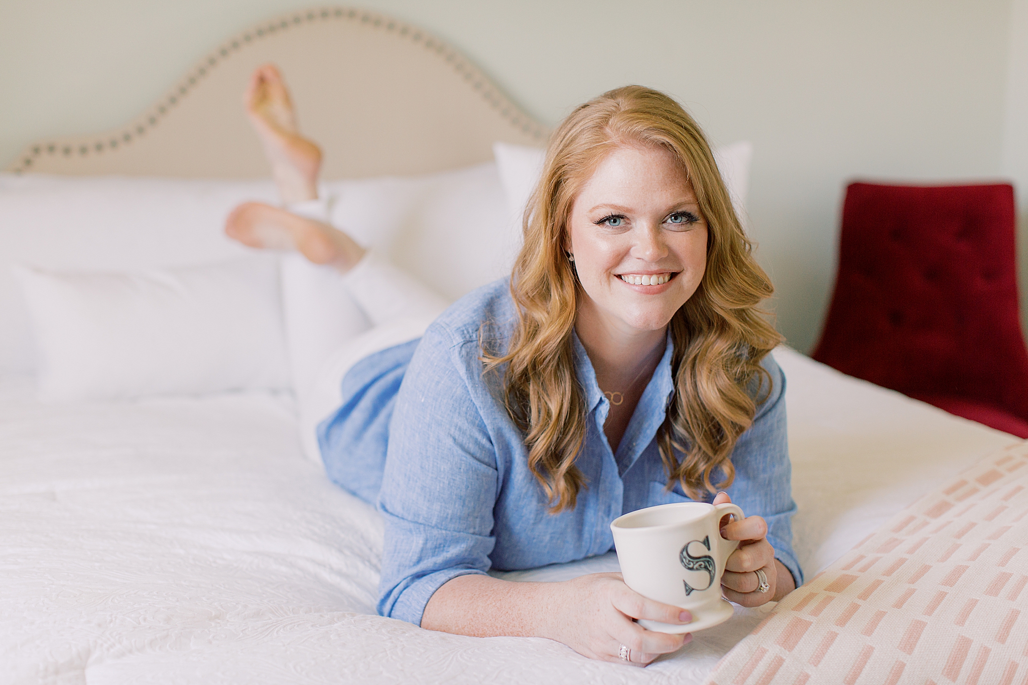 woman lays on bed with feet in the air during branding photos