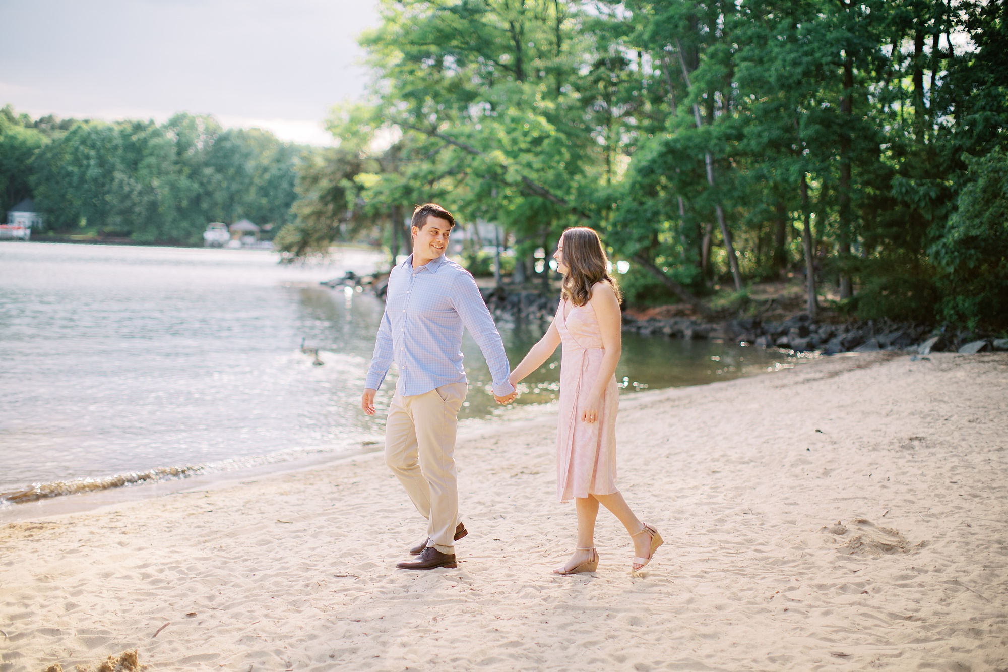 engaged couple walks on beach at Lake Norman