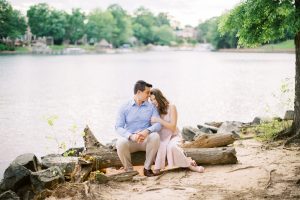 bride and groom sit on driftwood at Lake Norman