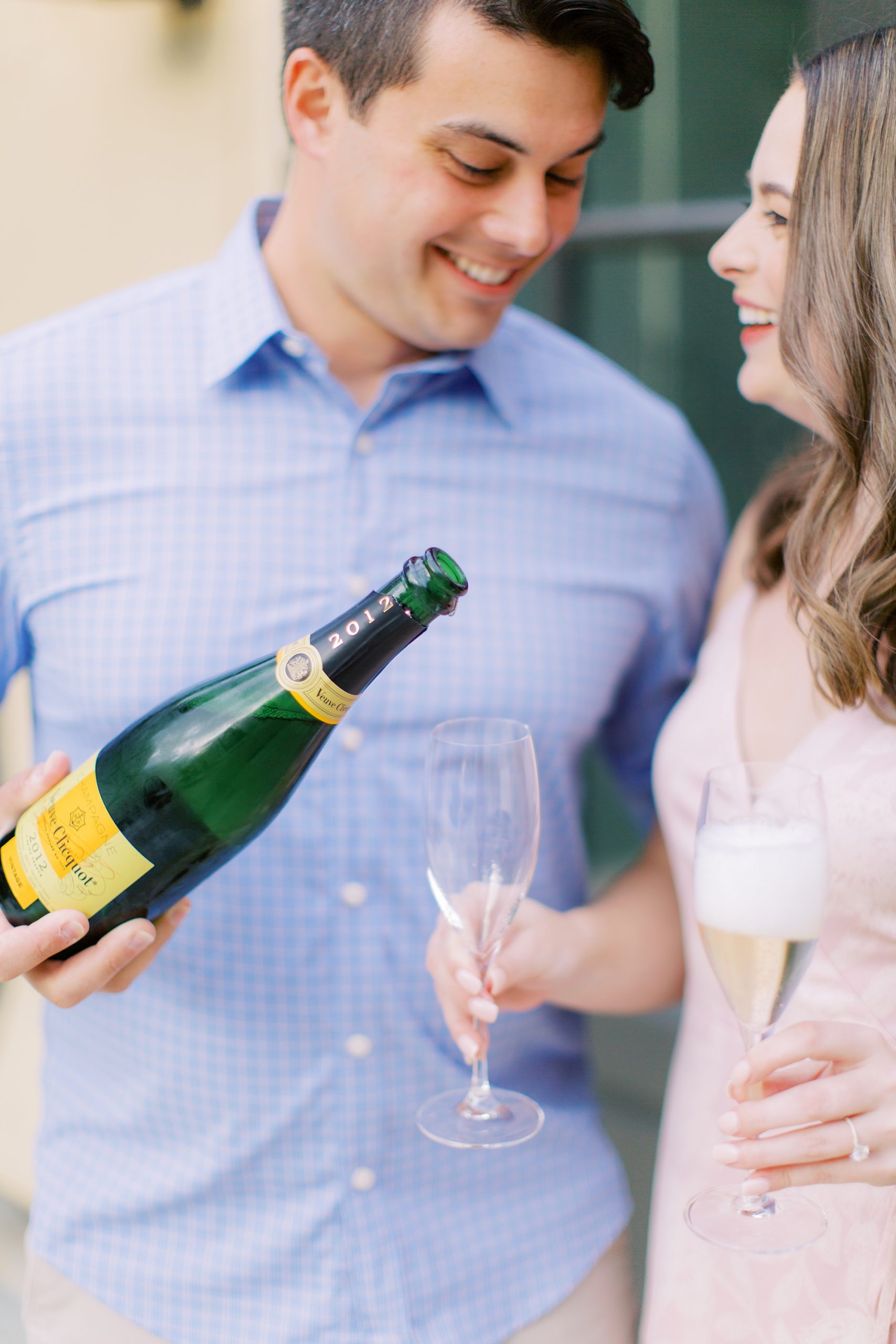 groom pours champagne for bride during Lake Norman engagement session