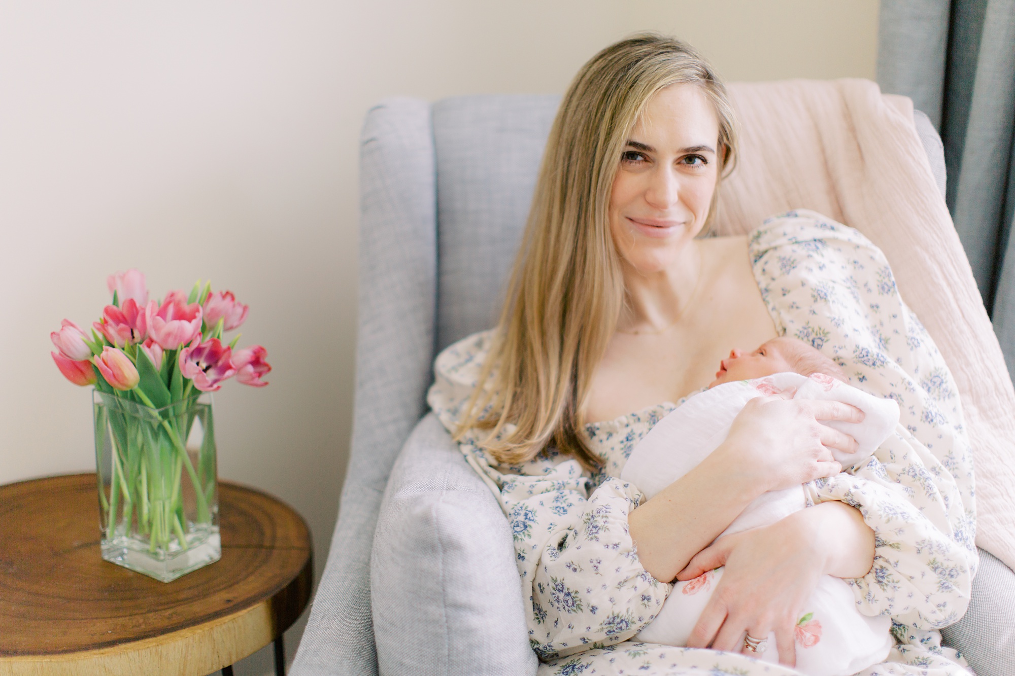 mom sits in nursery chair during lifestyle newborn photos