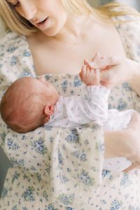 baby holds mom's hand during lifestyle newborn photos