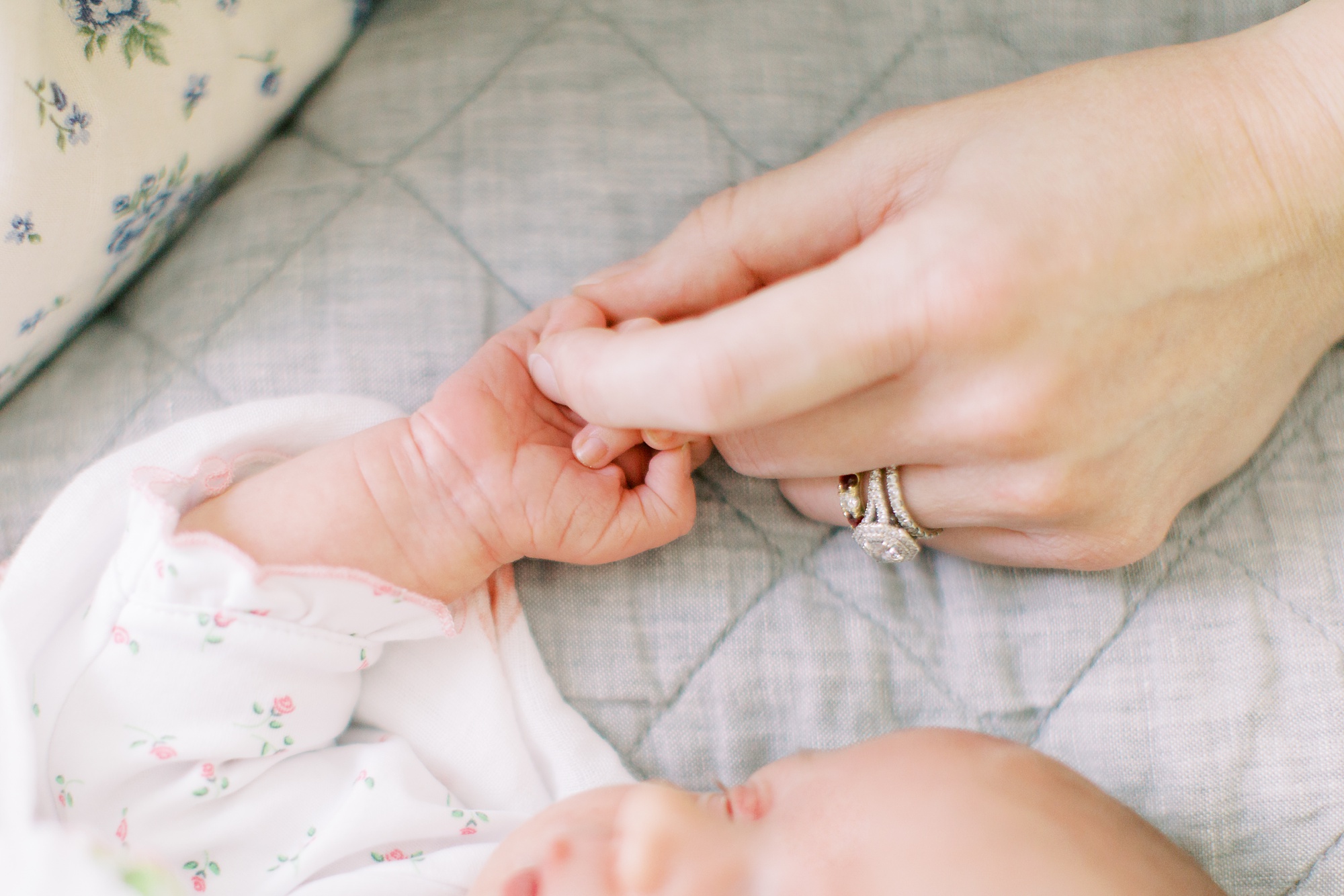 mom holds daughter's hand during newborn portraits in Charlotte NC