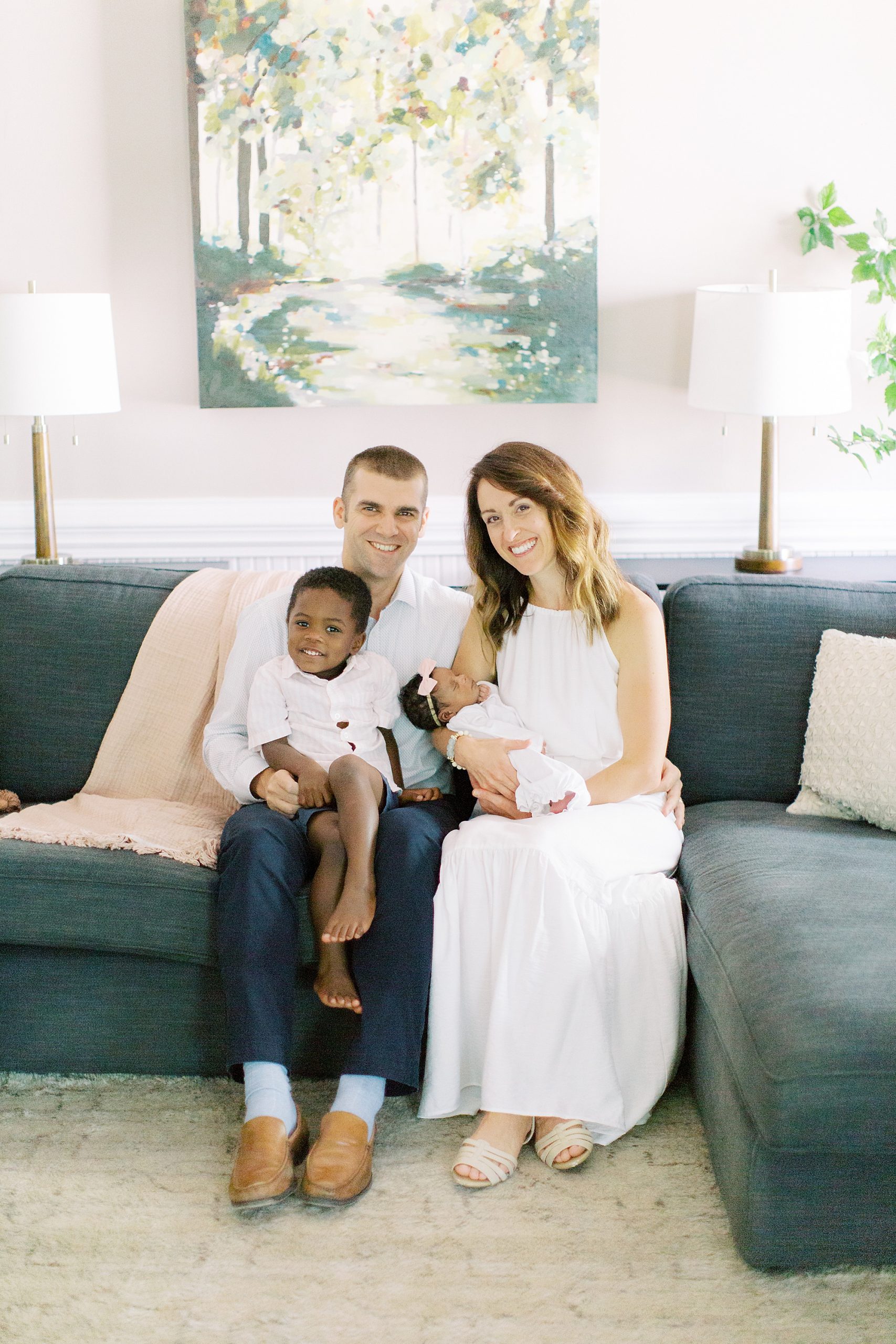 family sits on couch during Charlotte newborn session