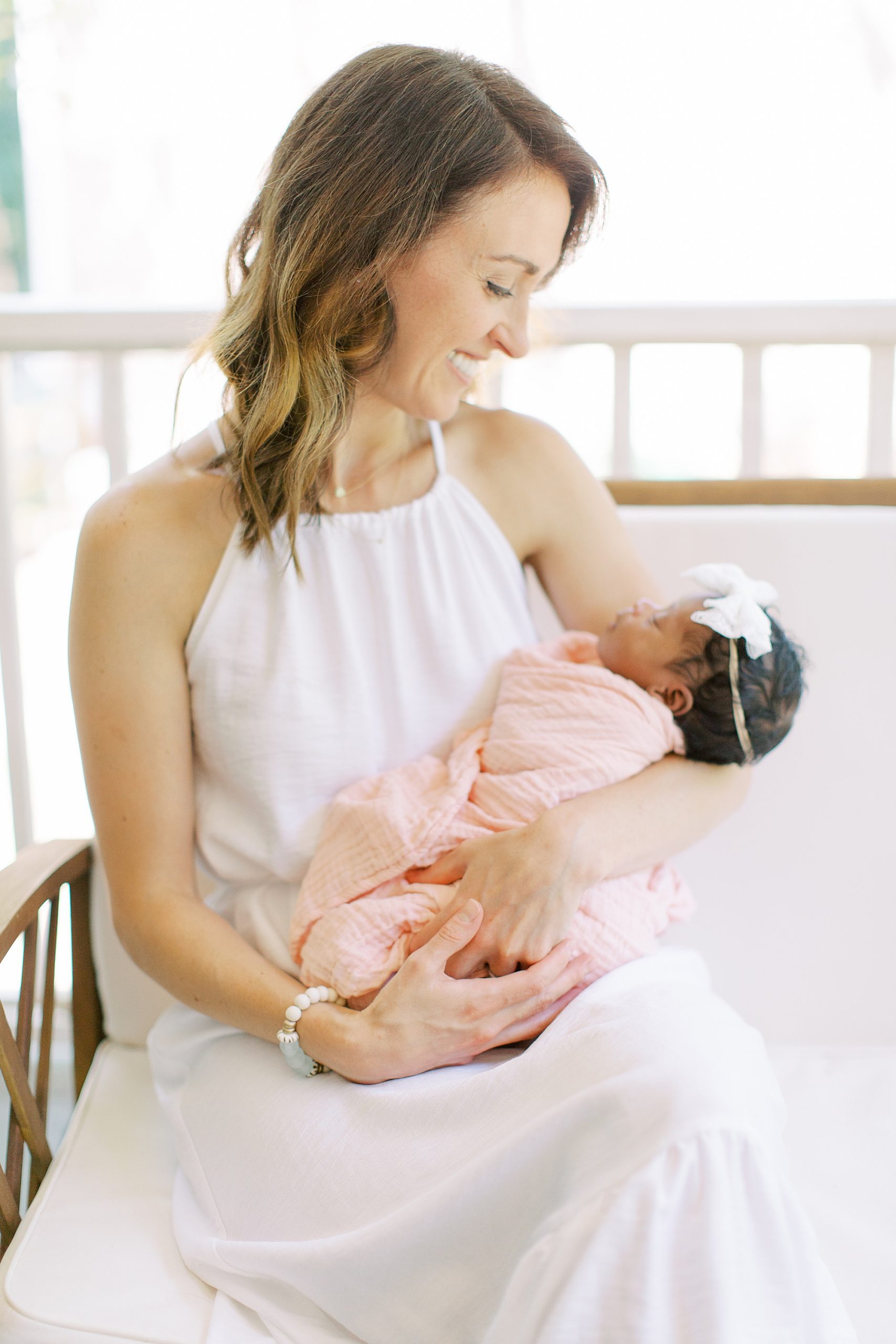 mom rocks daughter in pink wrap during Charlotte newborn session