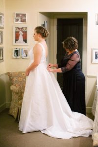 mother adjusts back of gown for bride