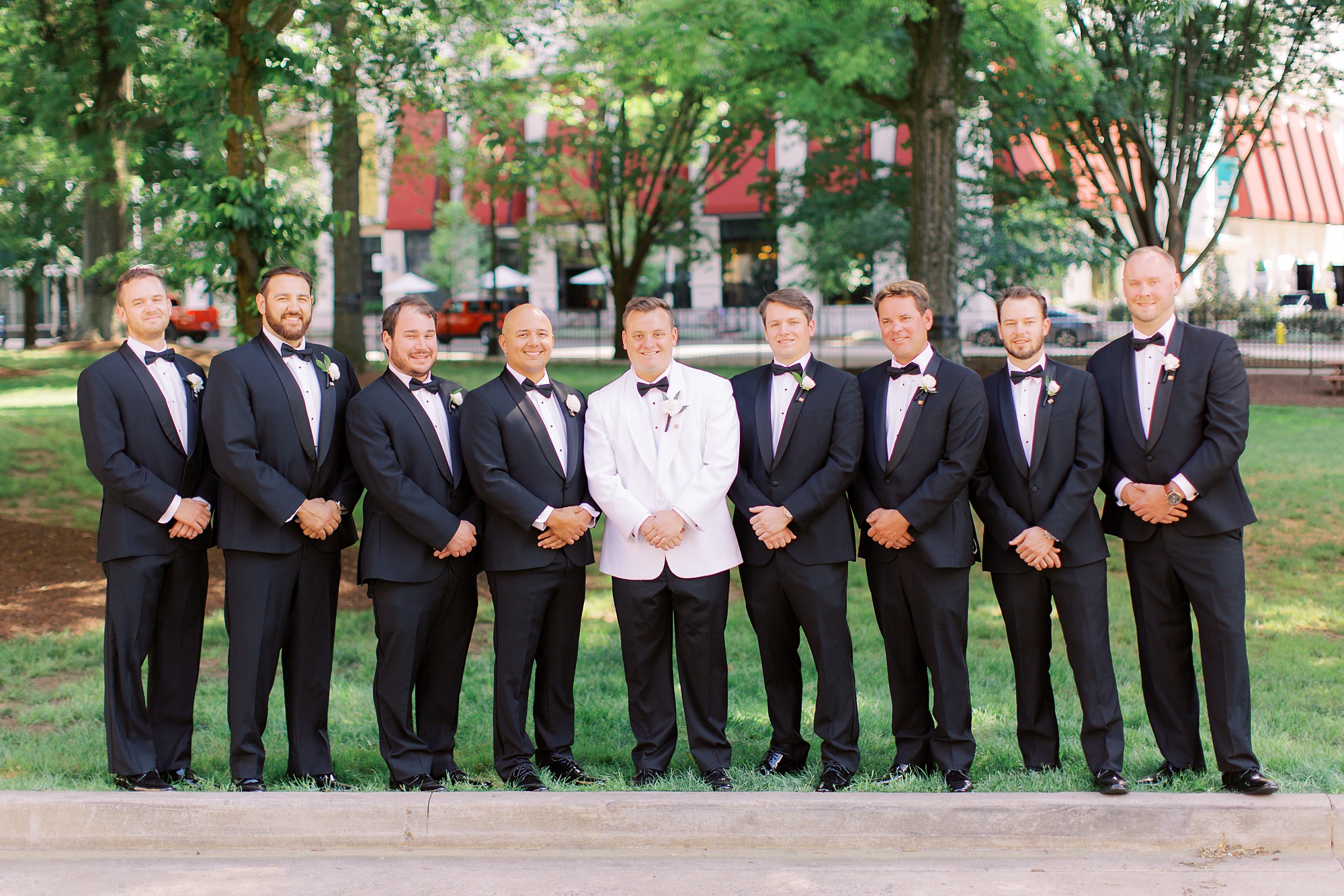 groom and groomsmen stand together in Charlotte park