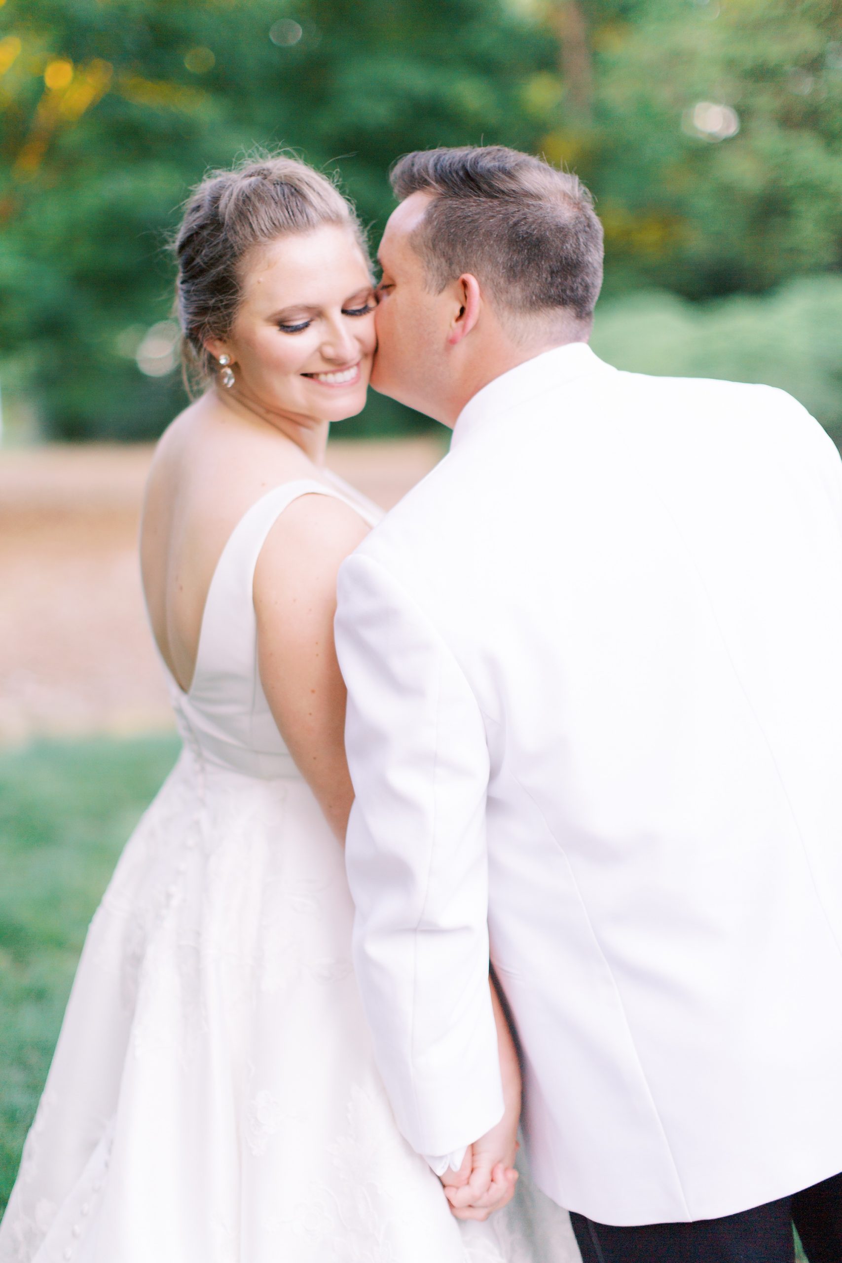 groom kisses bride's cheek during wedding portraits