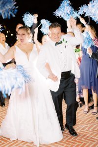 bride and groom leave wedding with guests cheering pom pops