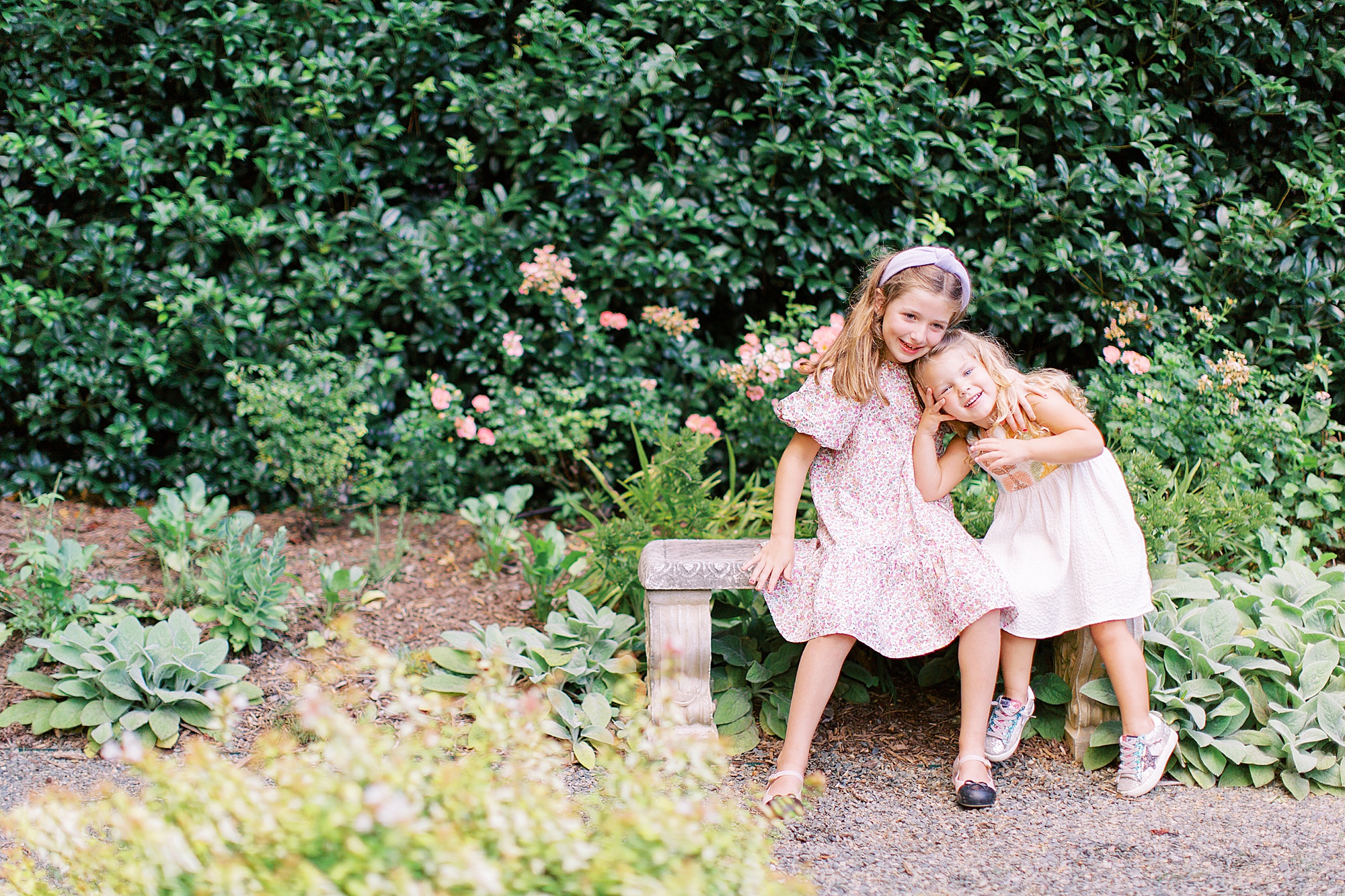 sisters ug on garden bench during Charlotte family session