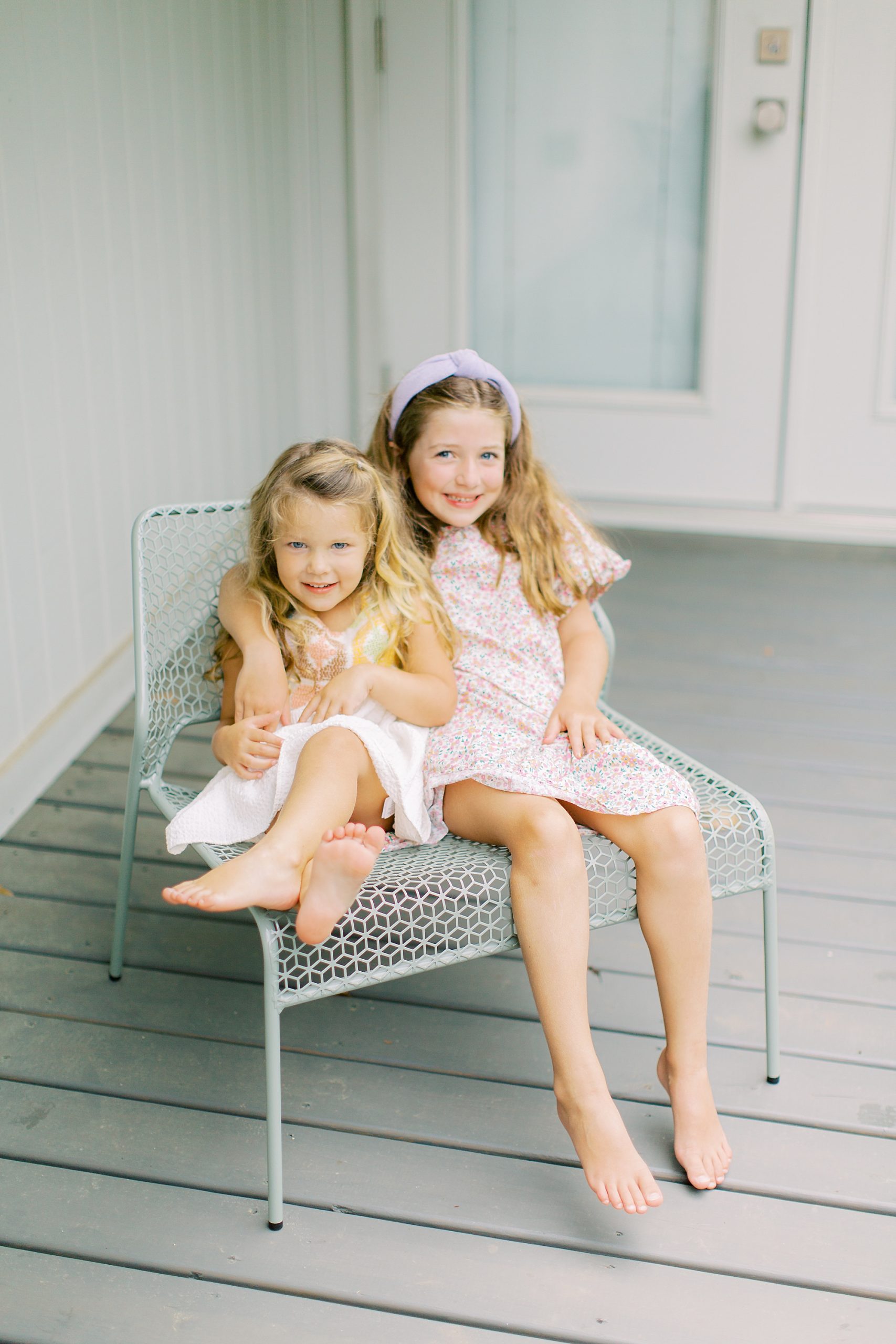 sisters hug on front porch during Charlotte family session