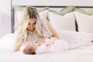 mom looks down at baby girl on bed during Charlotte NC newborn photos