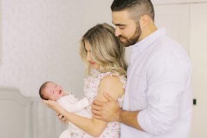 dad looks down at wife and daughter during Charlotte NC newborn photos