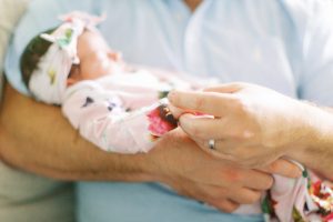 dad holds baby's hand during lifestyle newborn session in Charlotte NC