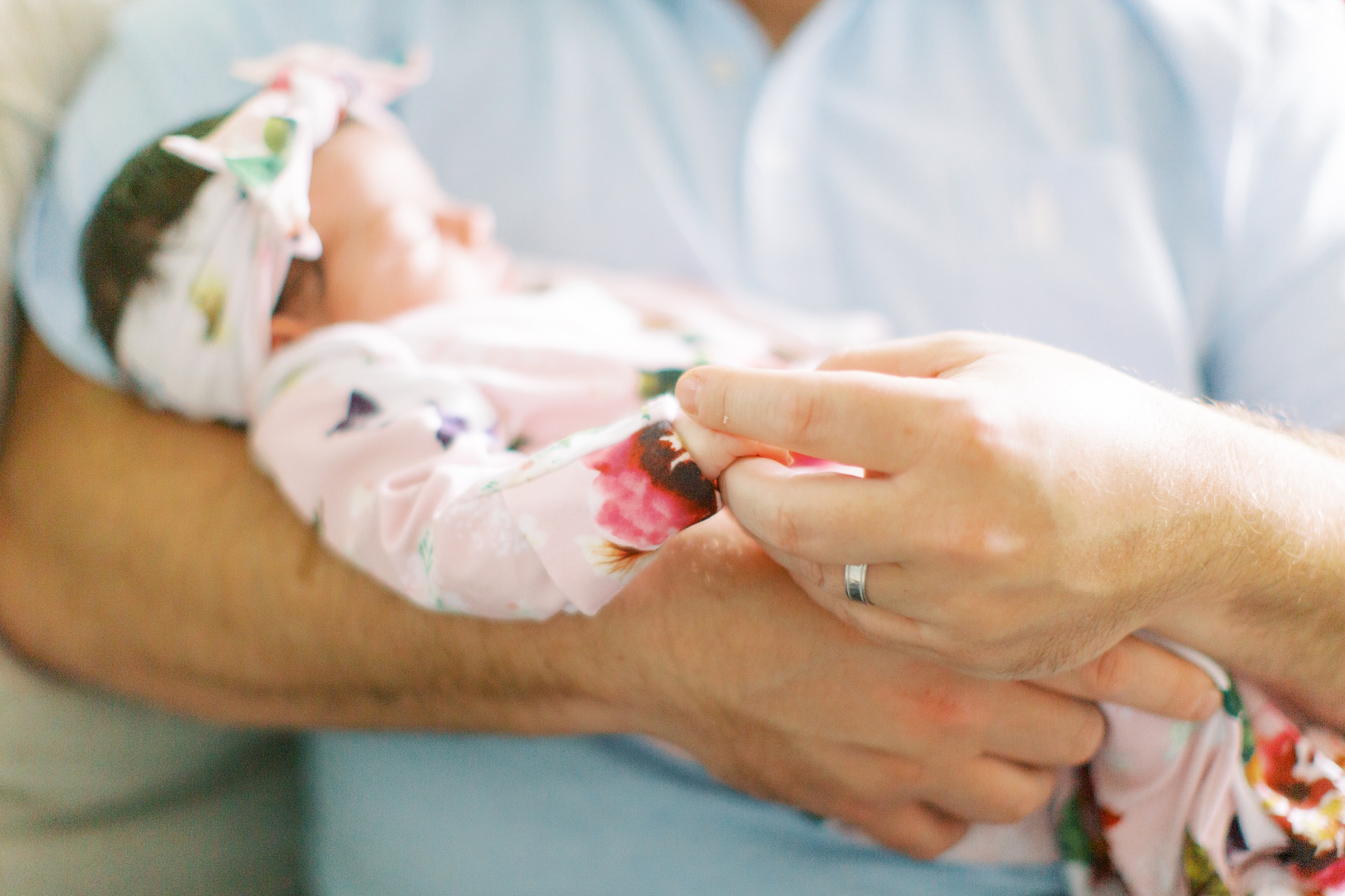 dad holds baby's hand during lifestyle newborn session in Charlotte NC