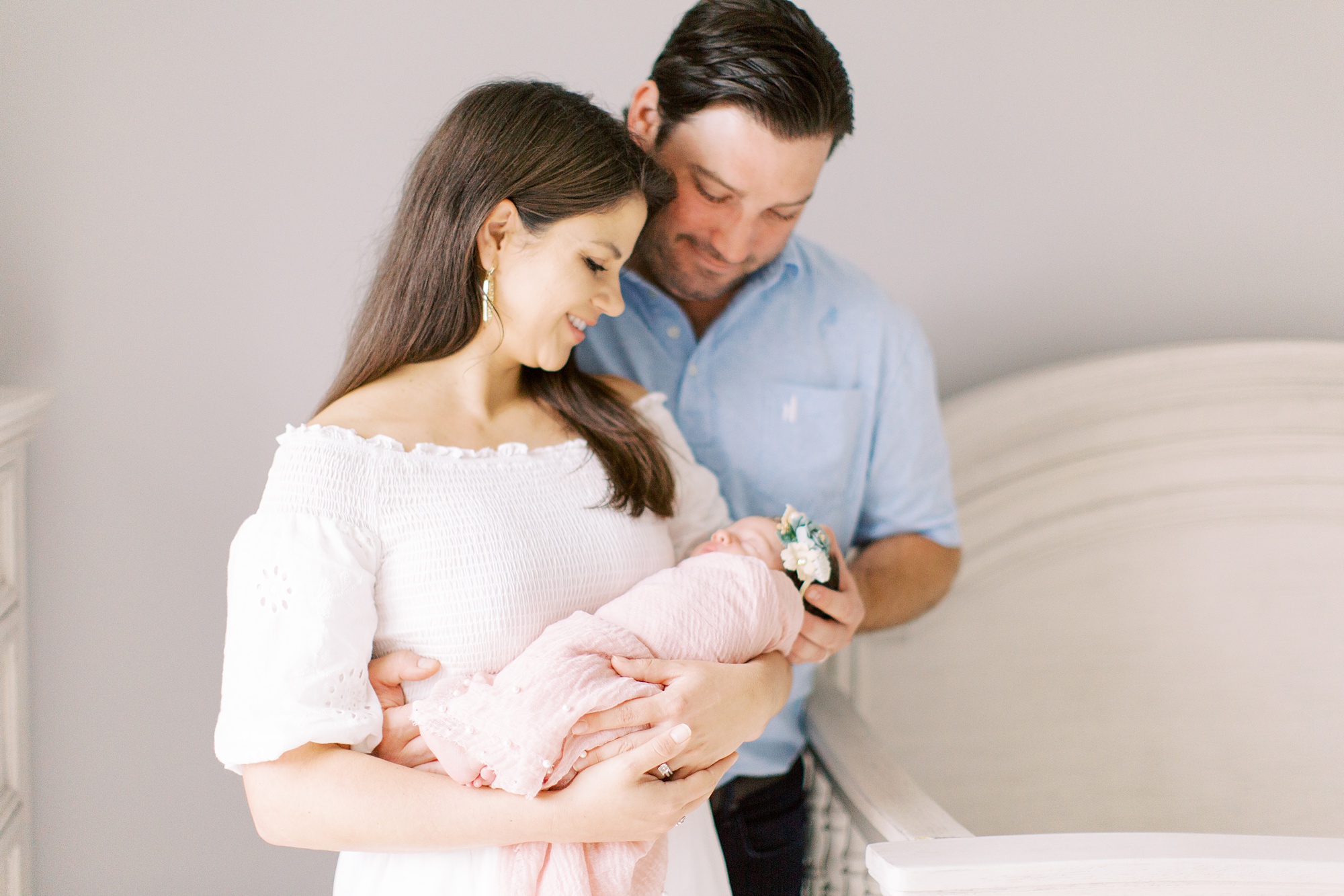 new parents look down at baby girl during newborn photos at home