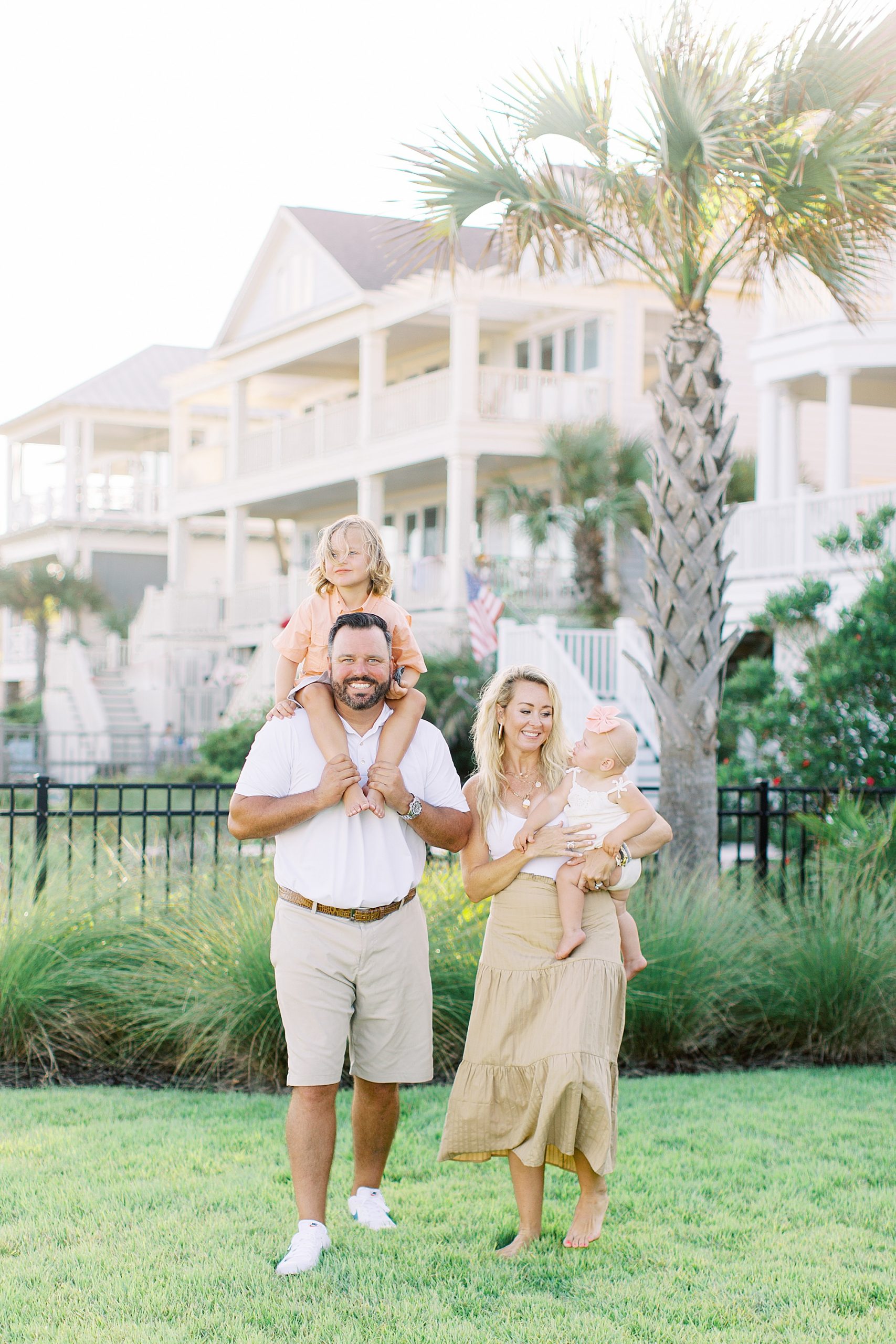 family of four poses by palm tree at beach house in Charleston SC