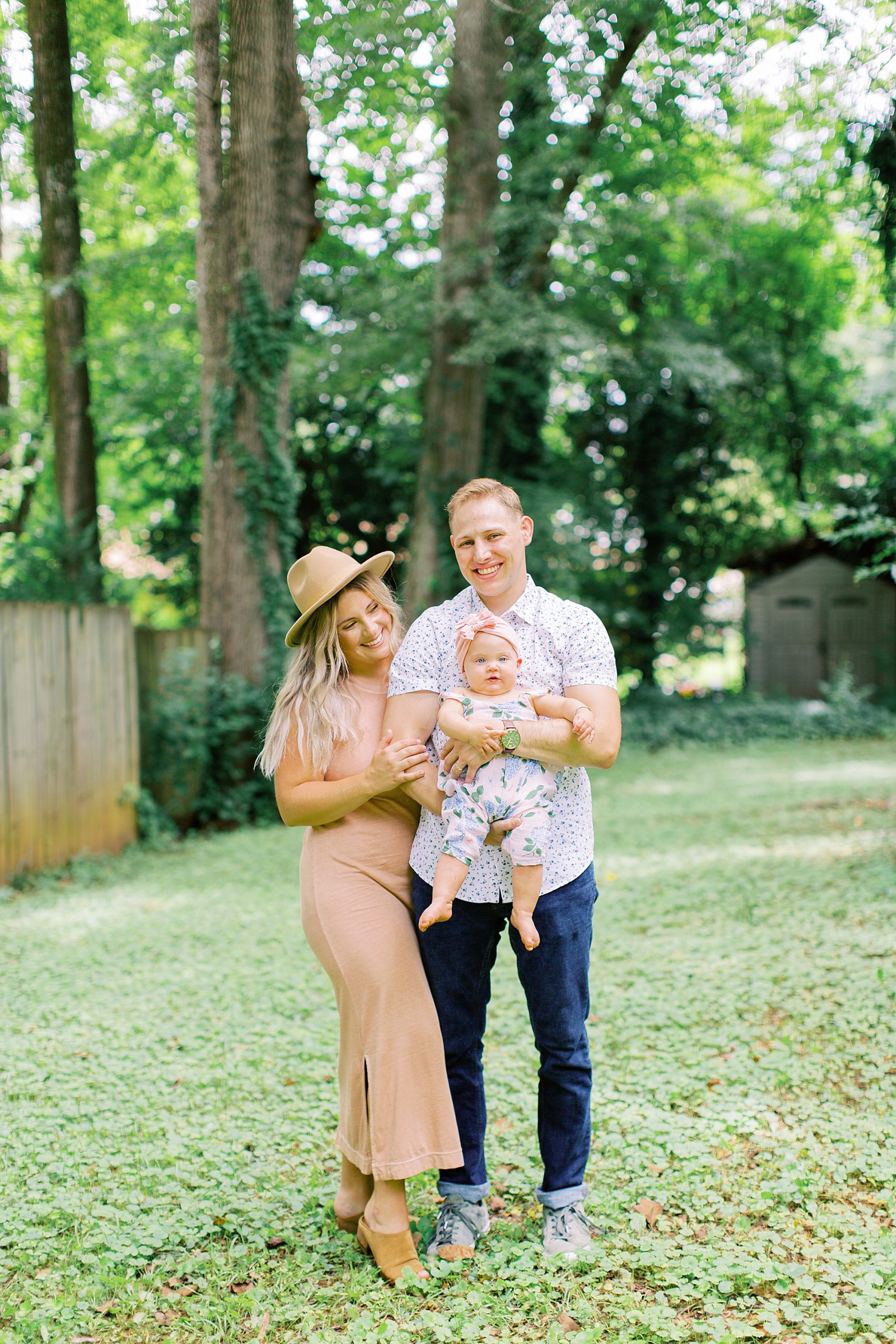 family of three poses in Atlanta backyard during family photos