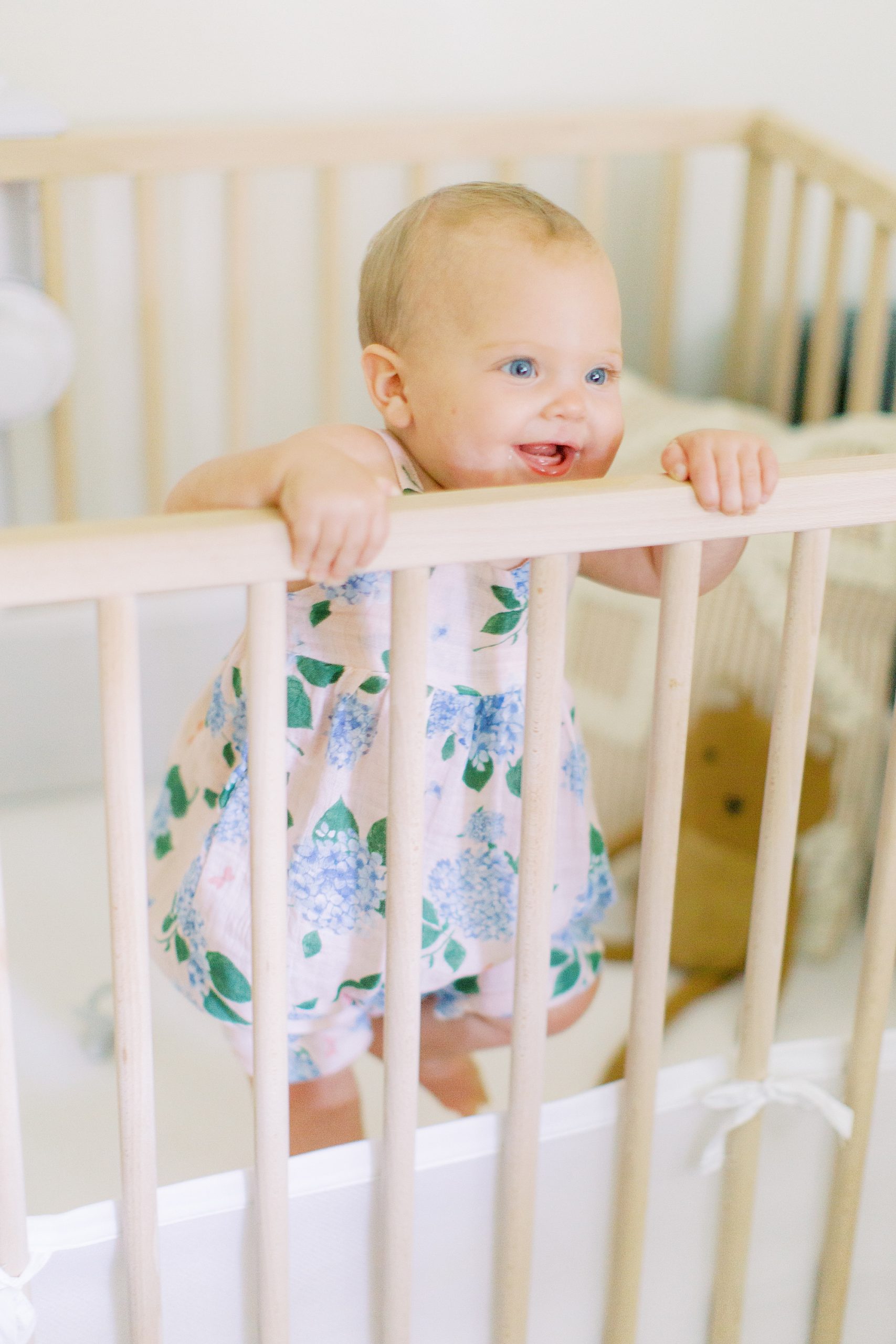 baby stands in crib during Atlanta family photos in nursery