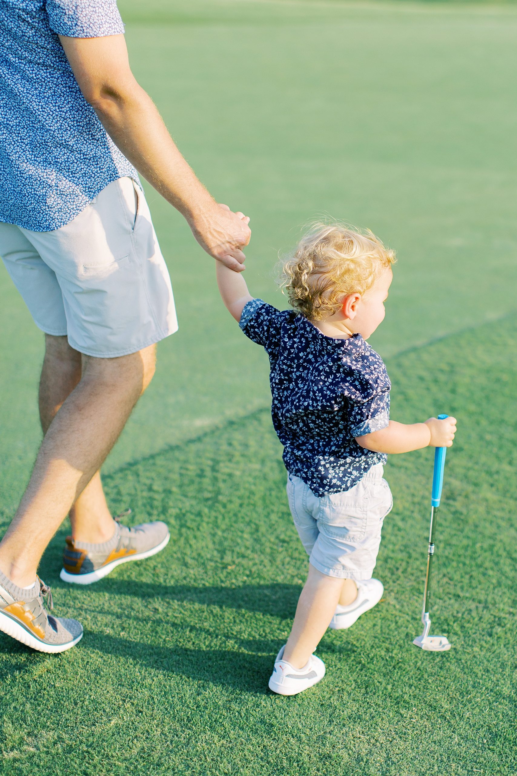 dad walks with son along green at Cabarrus Country Club
