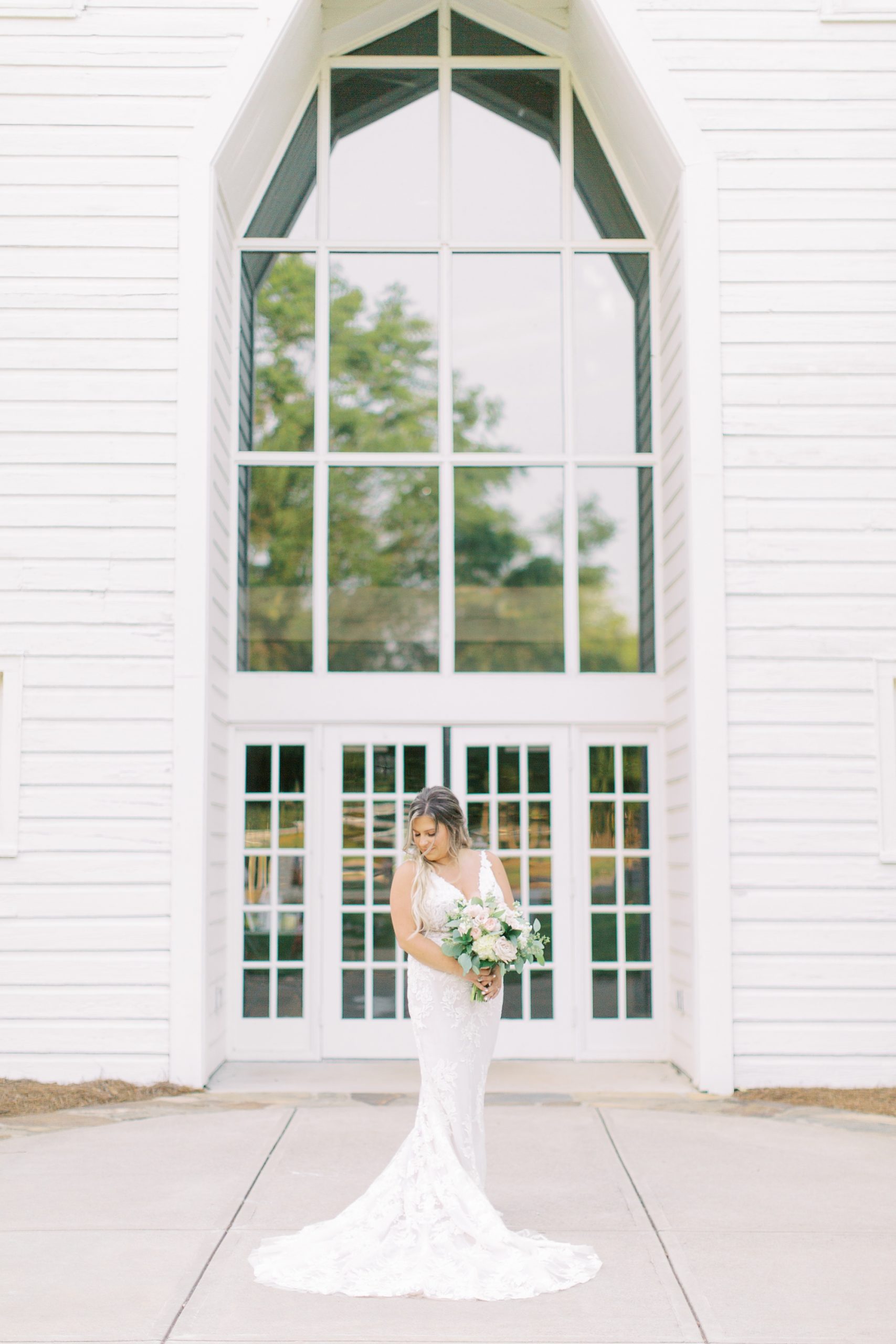 bride holds bouquet and looks over shoulder outside window of The Dairy Barn