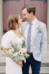 married couple smiles at each other during portraits outside The Palmer Building