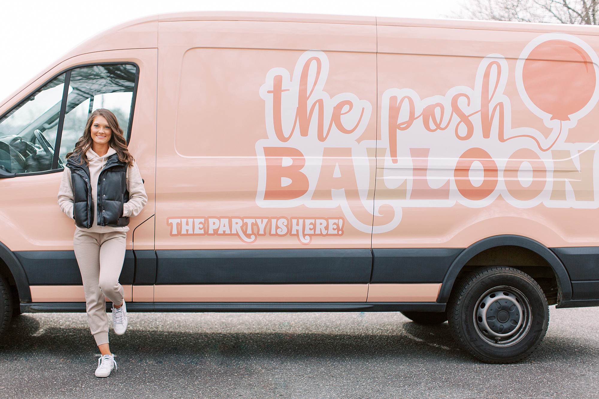 woman leans against pink van during balloon artist branding session