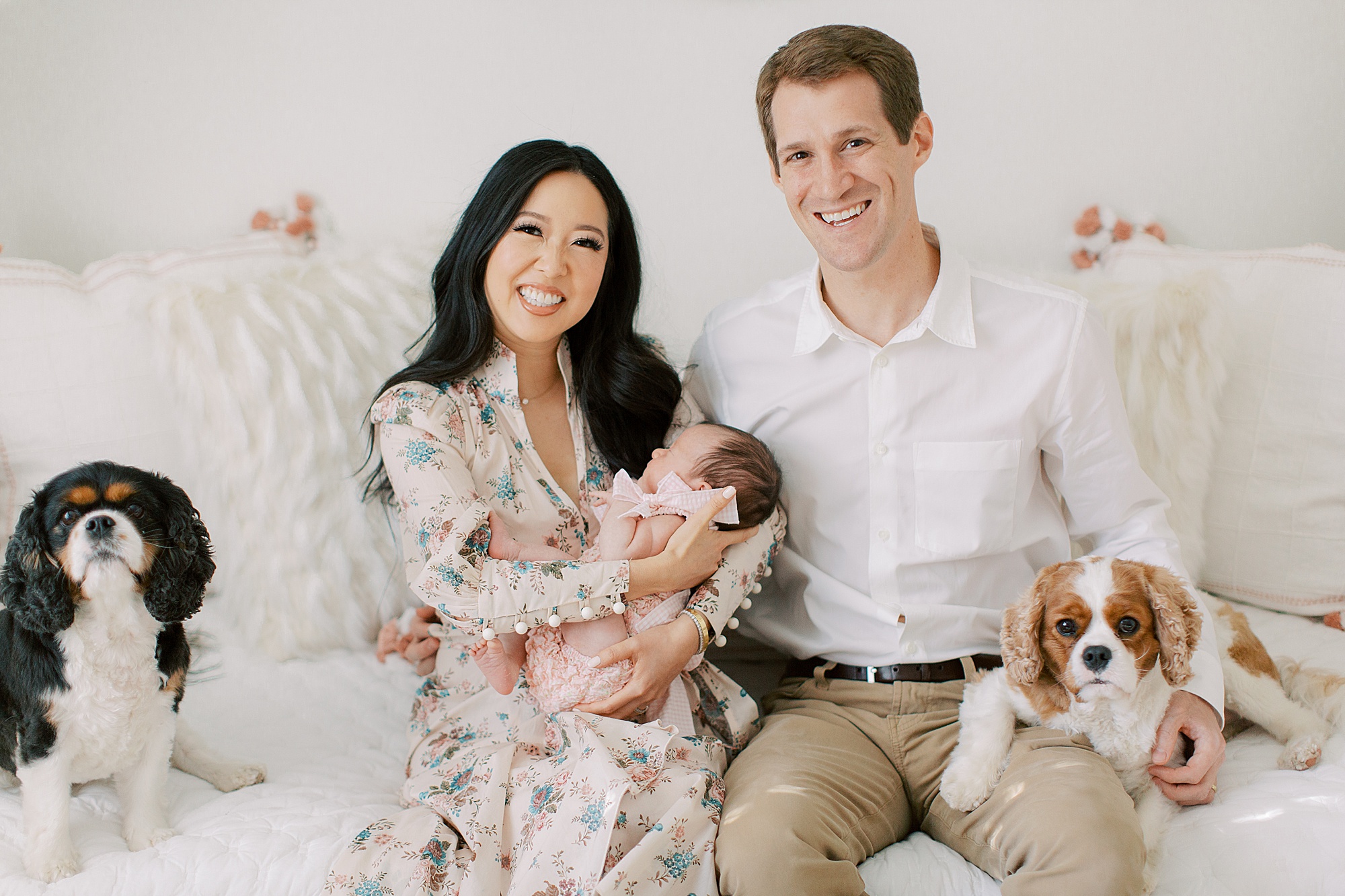 family with two dogs holds newborn baby girl during at-home newborn portraits