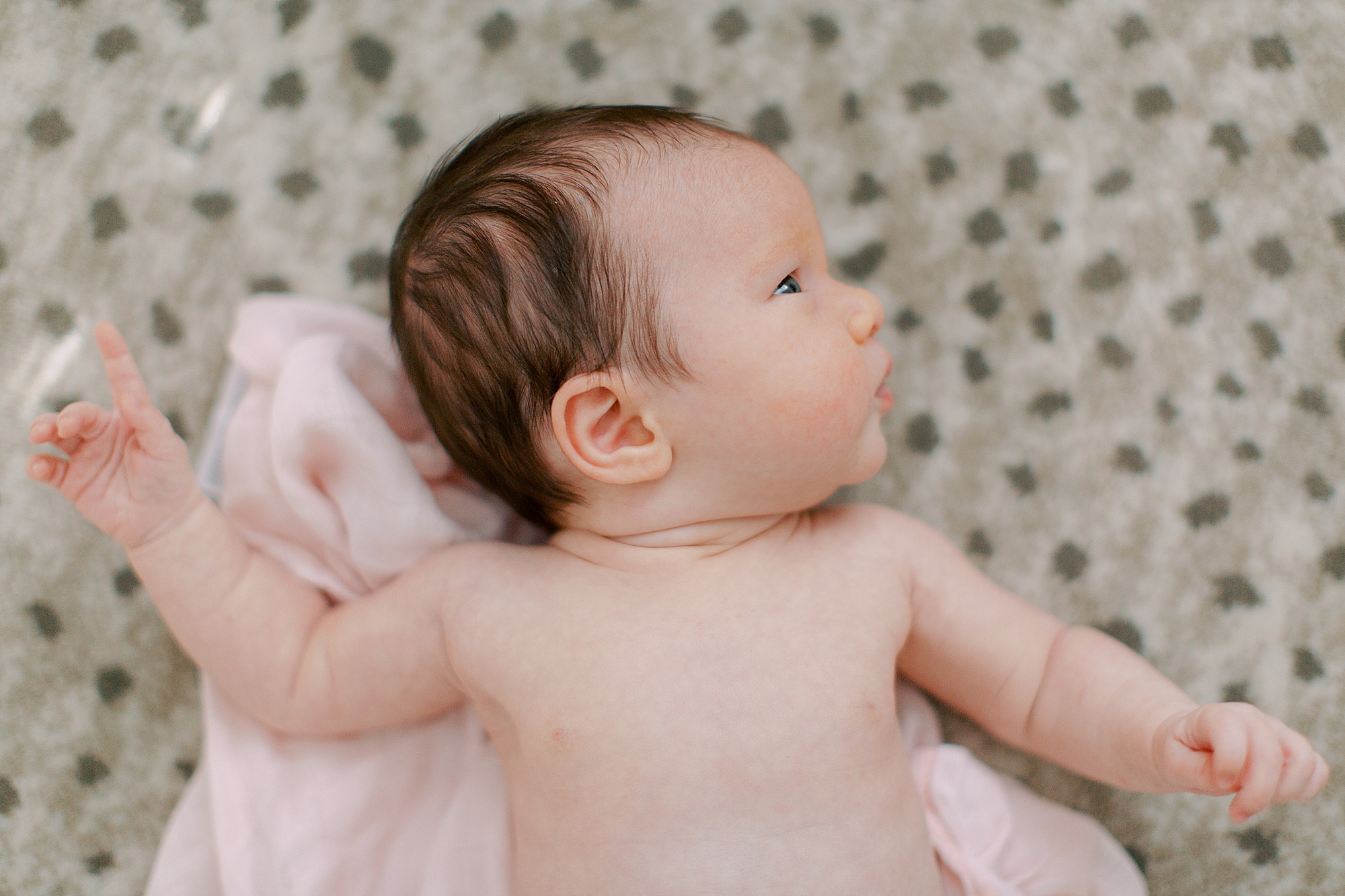 baby girl lays on rug during newborn photos at home