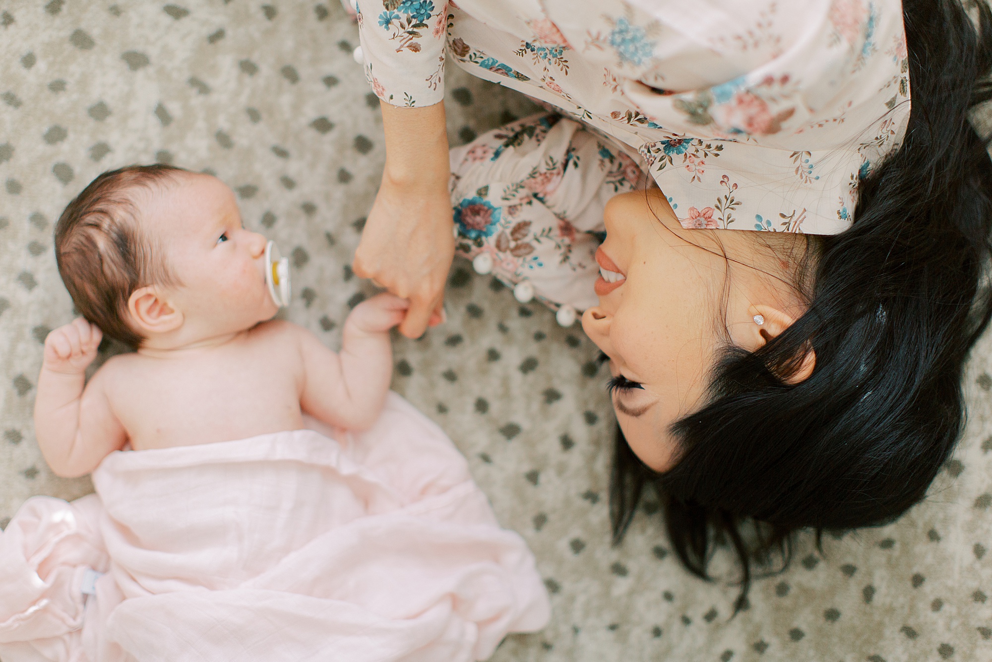 baby and mom lay on rug during family portraits