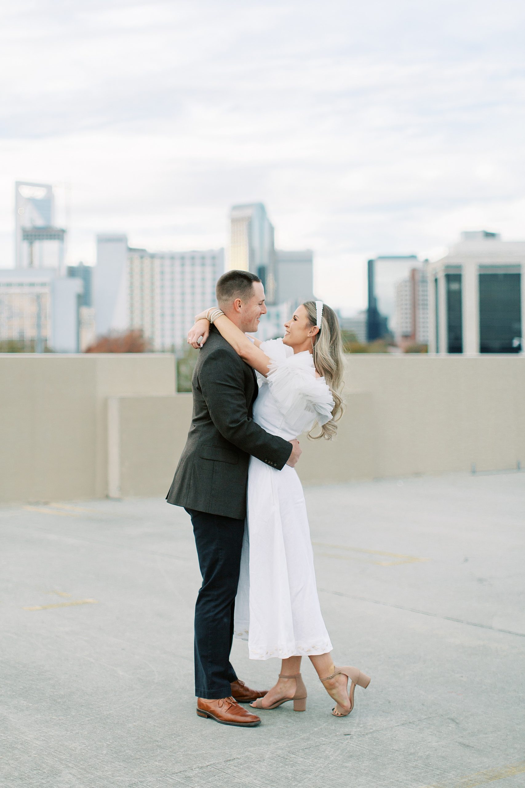 woman in white dress hugs man during Charlotte NC engagement session