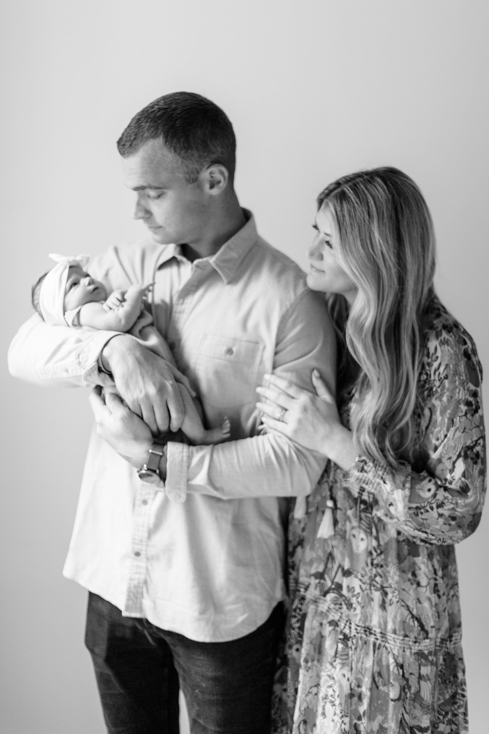 parents look at baby girl in dad's arms during Charlotte newborn session