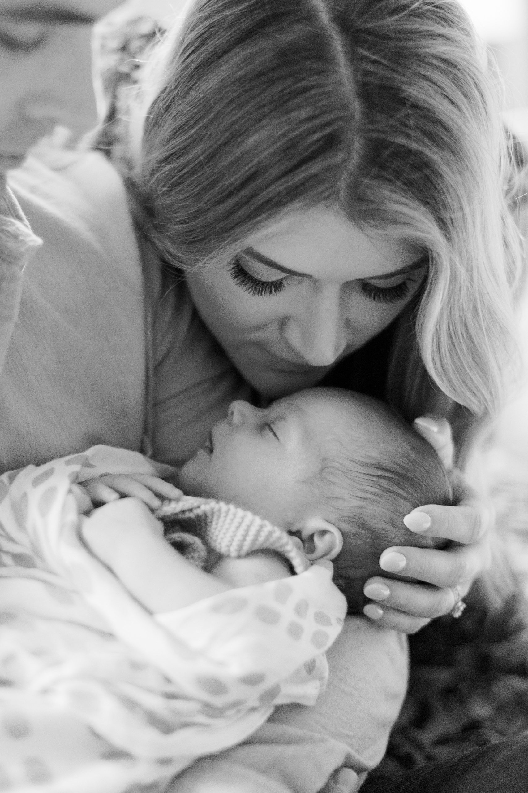 mom leans to kiss daughter during Charlotte newborn session