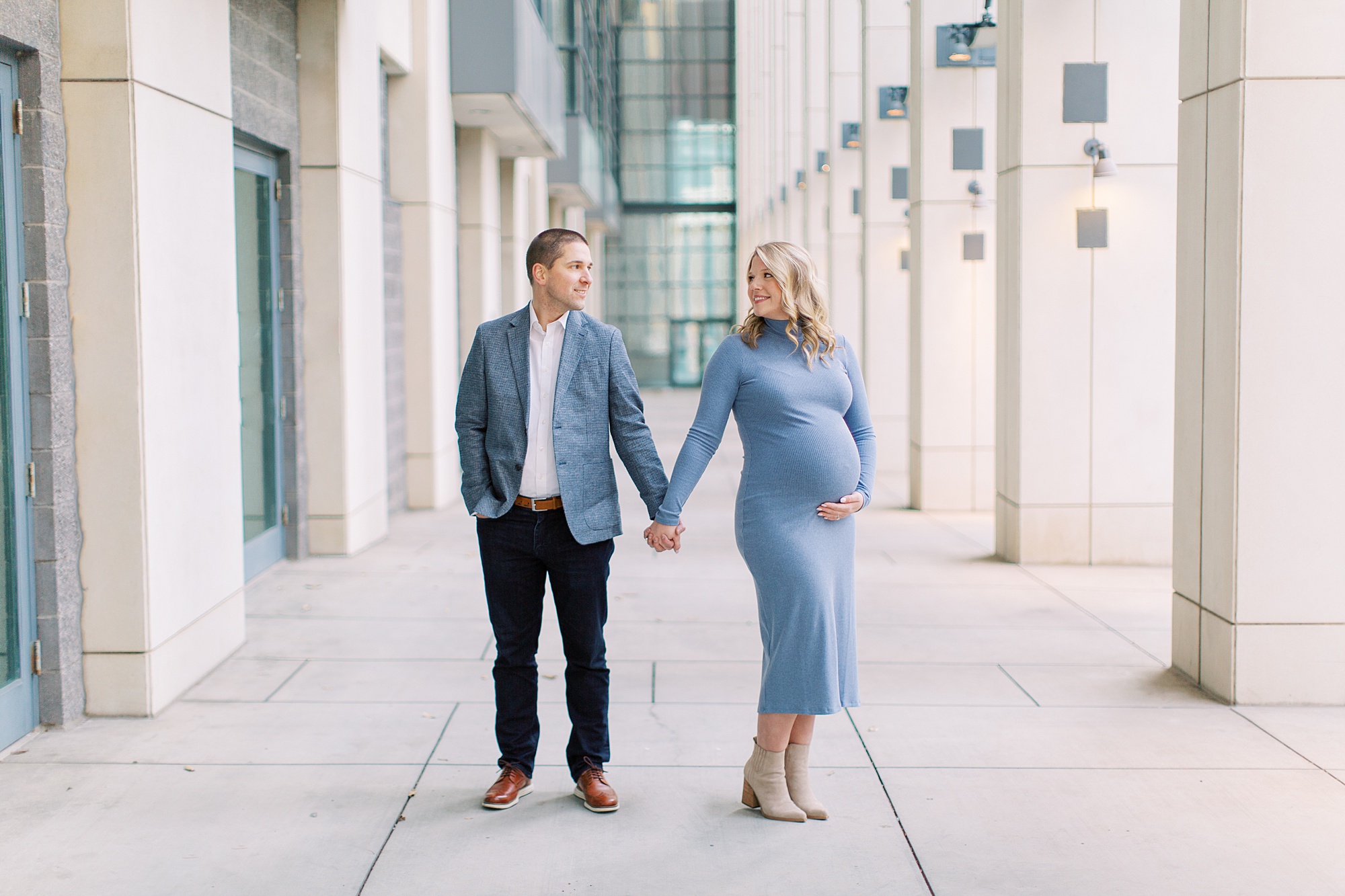 couple holds hands facing apart during maternity photos in Charlotte NC