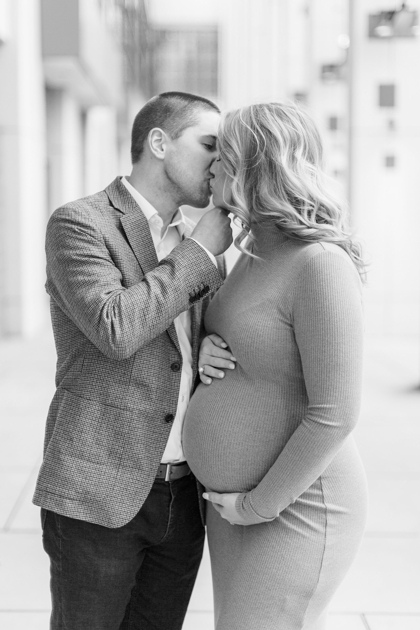 couple kisses during winter Uptown Charlotte maternity session