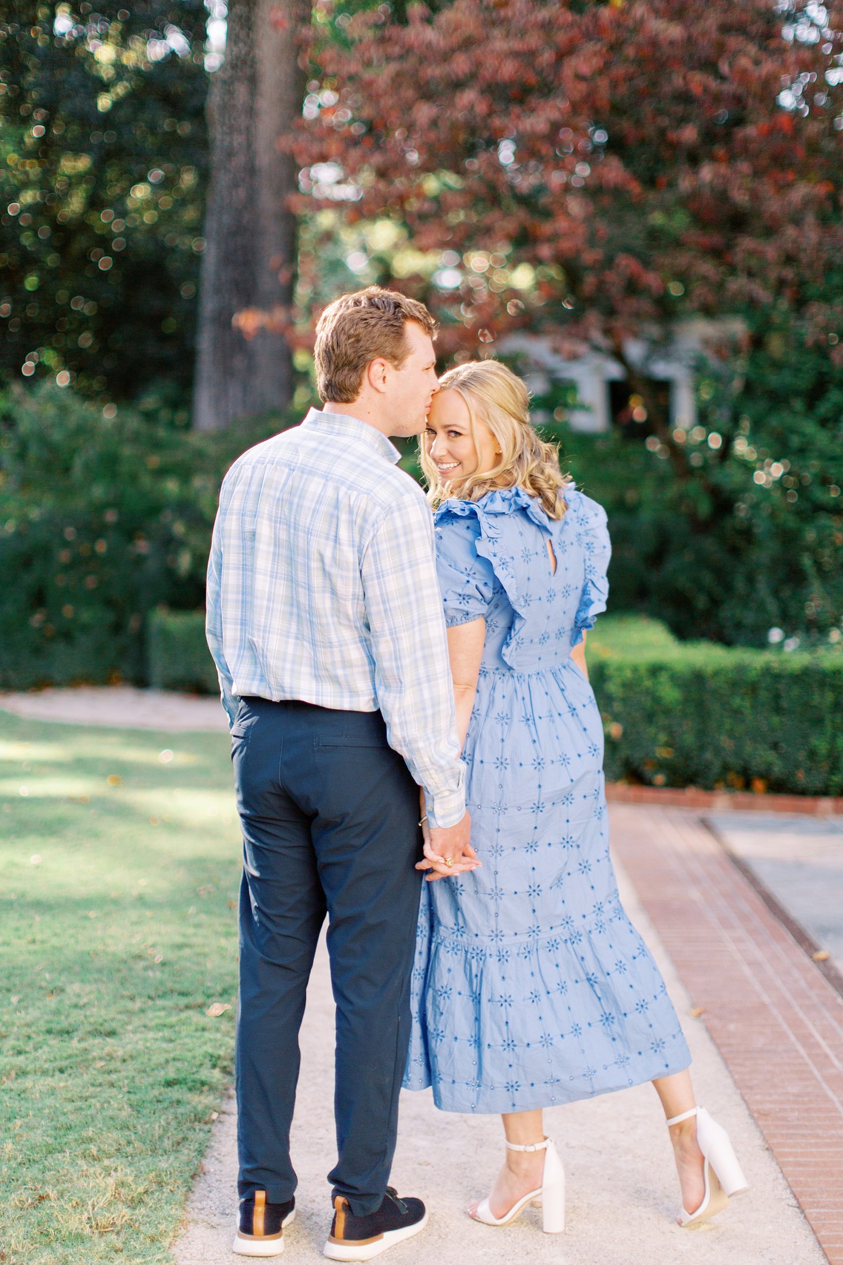 man kisses woman in blue dress in gardens of Charlotte NC venue