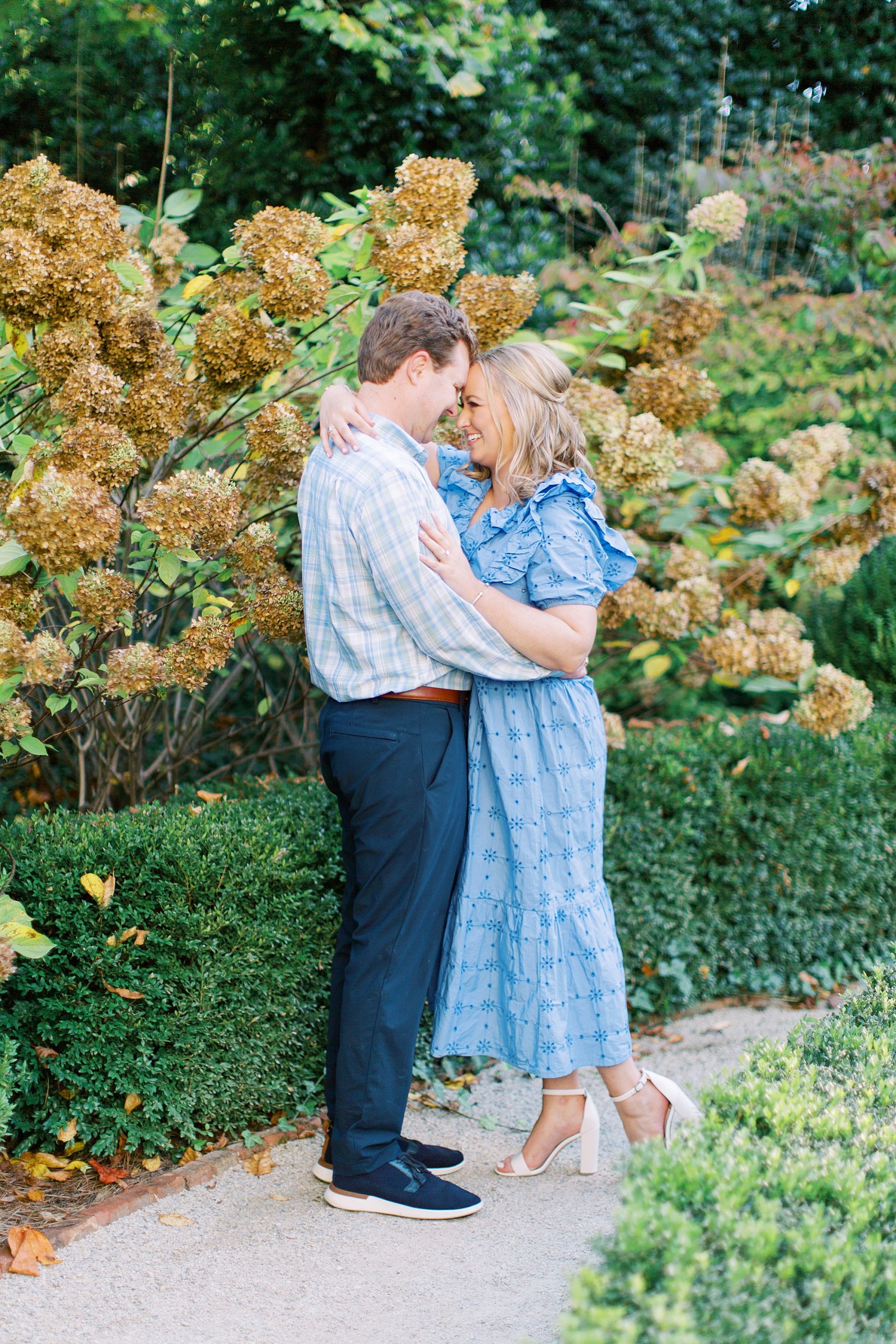 bride and groom hug in garden during spring engagement session