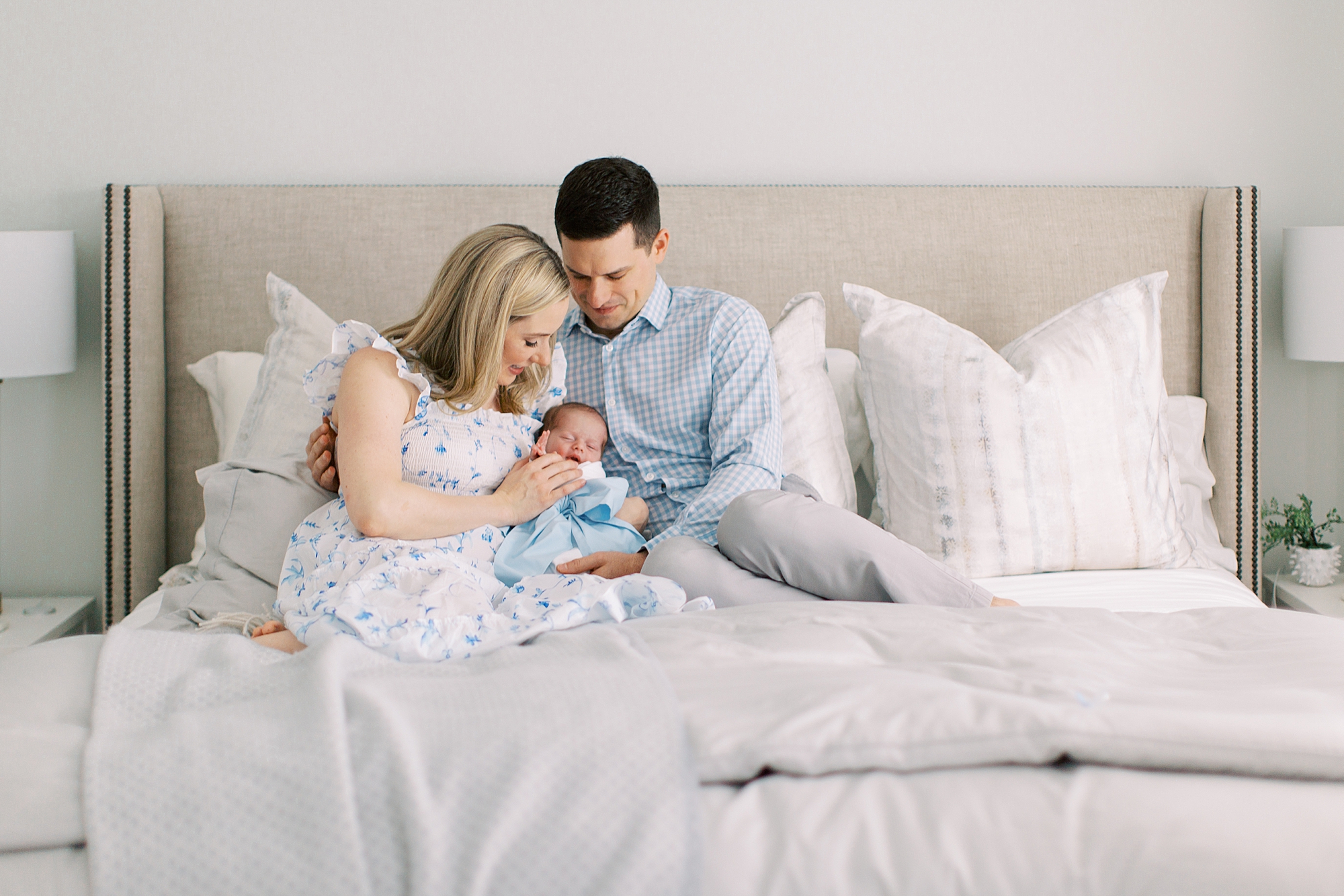 new parents snuggle with baby on bed during lifestyle newborn session