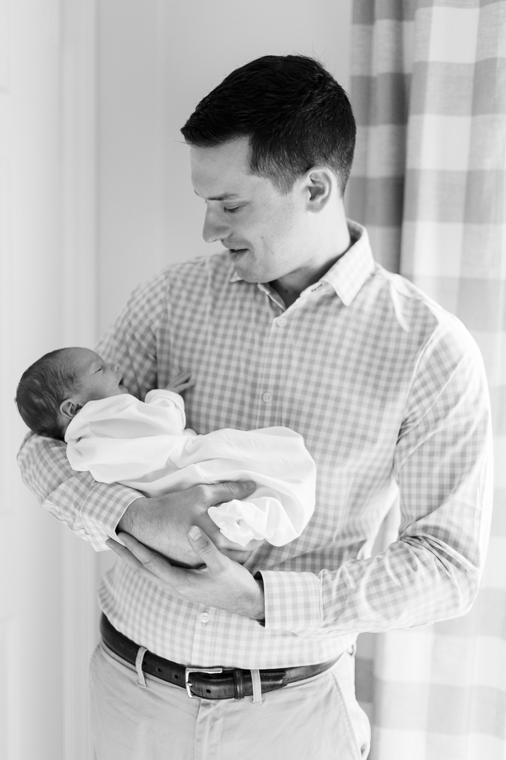 dad holds baby boy during newborn photos at home