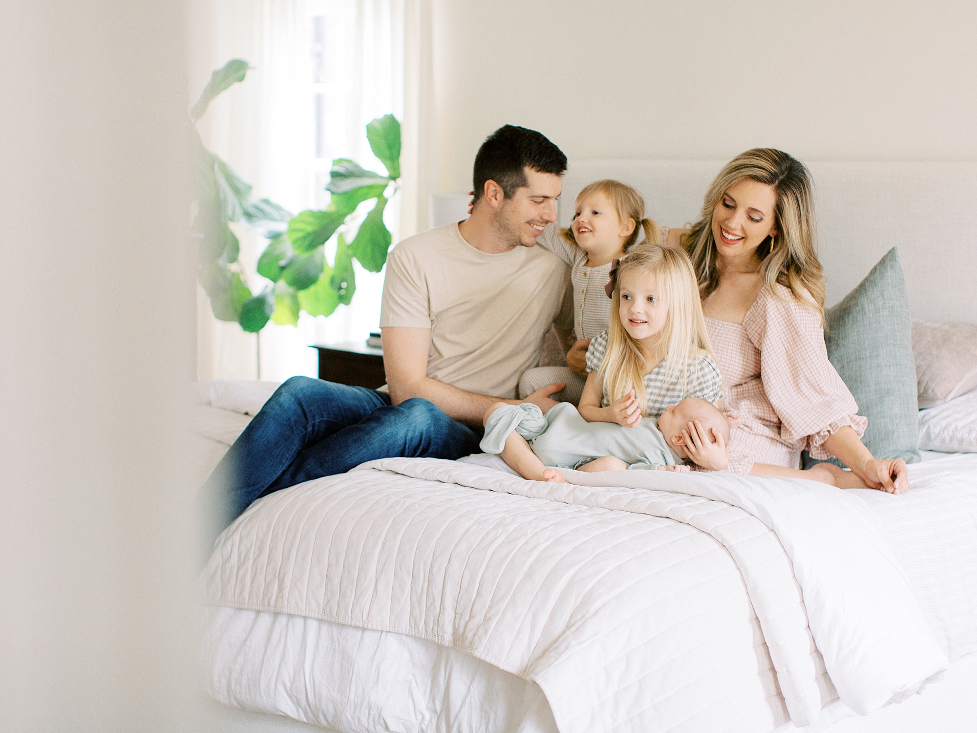 family of five sits on bed during lifestyle newborn photos