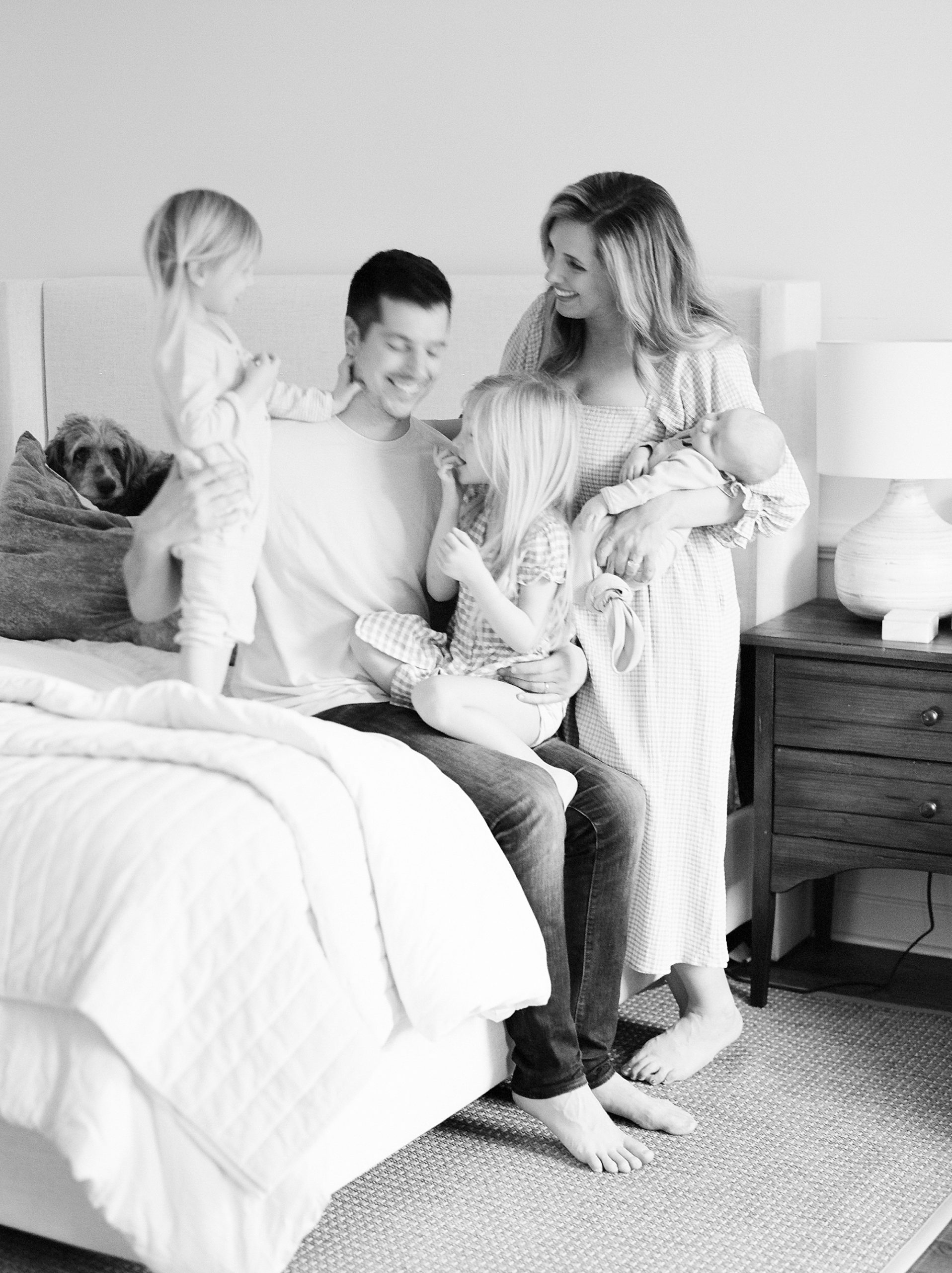 girls climb on dad while mom holds son in bedroom