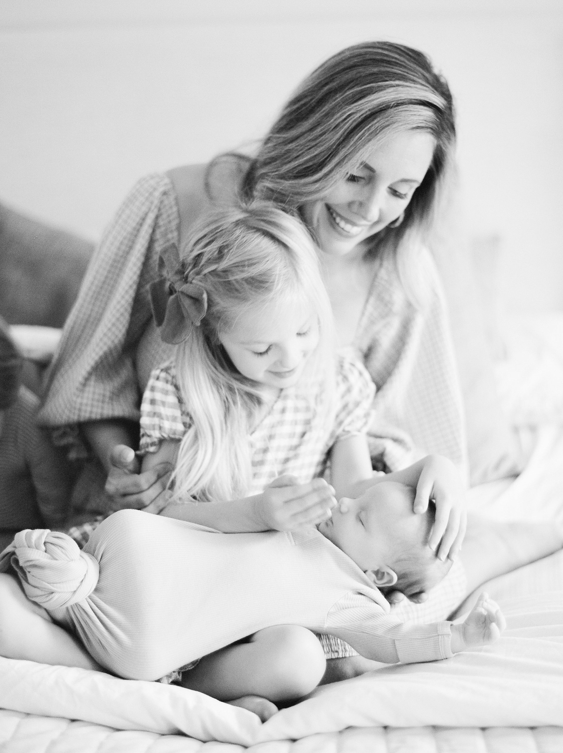 mom looks down at daughter holding son during Charleston SC newborn session