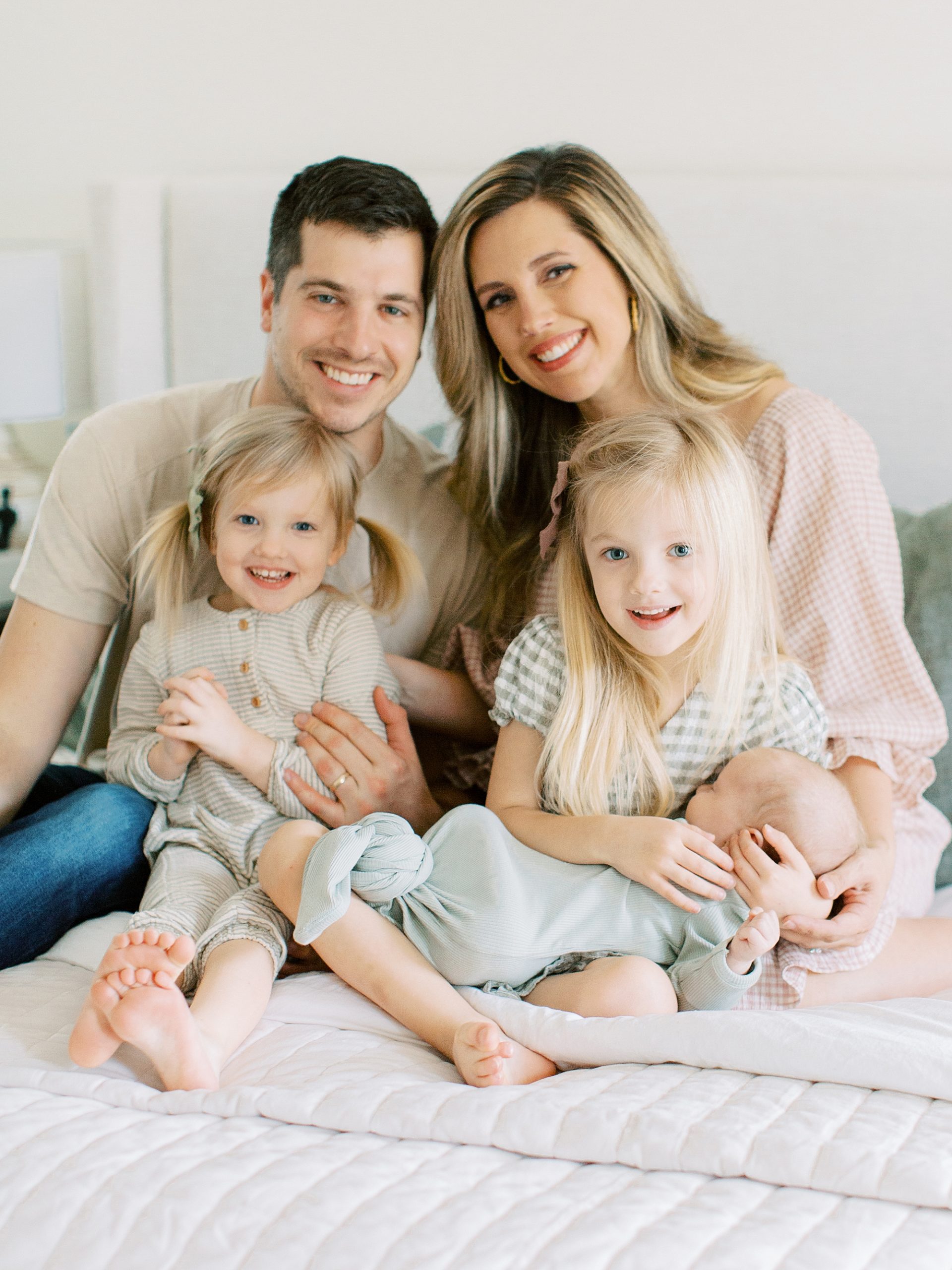 family of five sits together on bed during lifestyle Charleston SC newborn session
